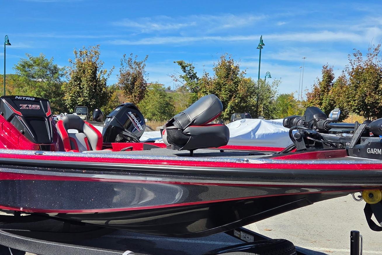 Red Nitro Z18 Pro 2026 boat with Mercury engine, parked outdoors under blue sky.