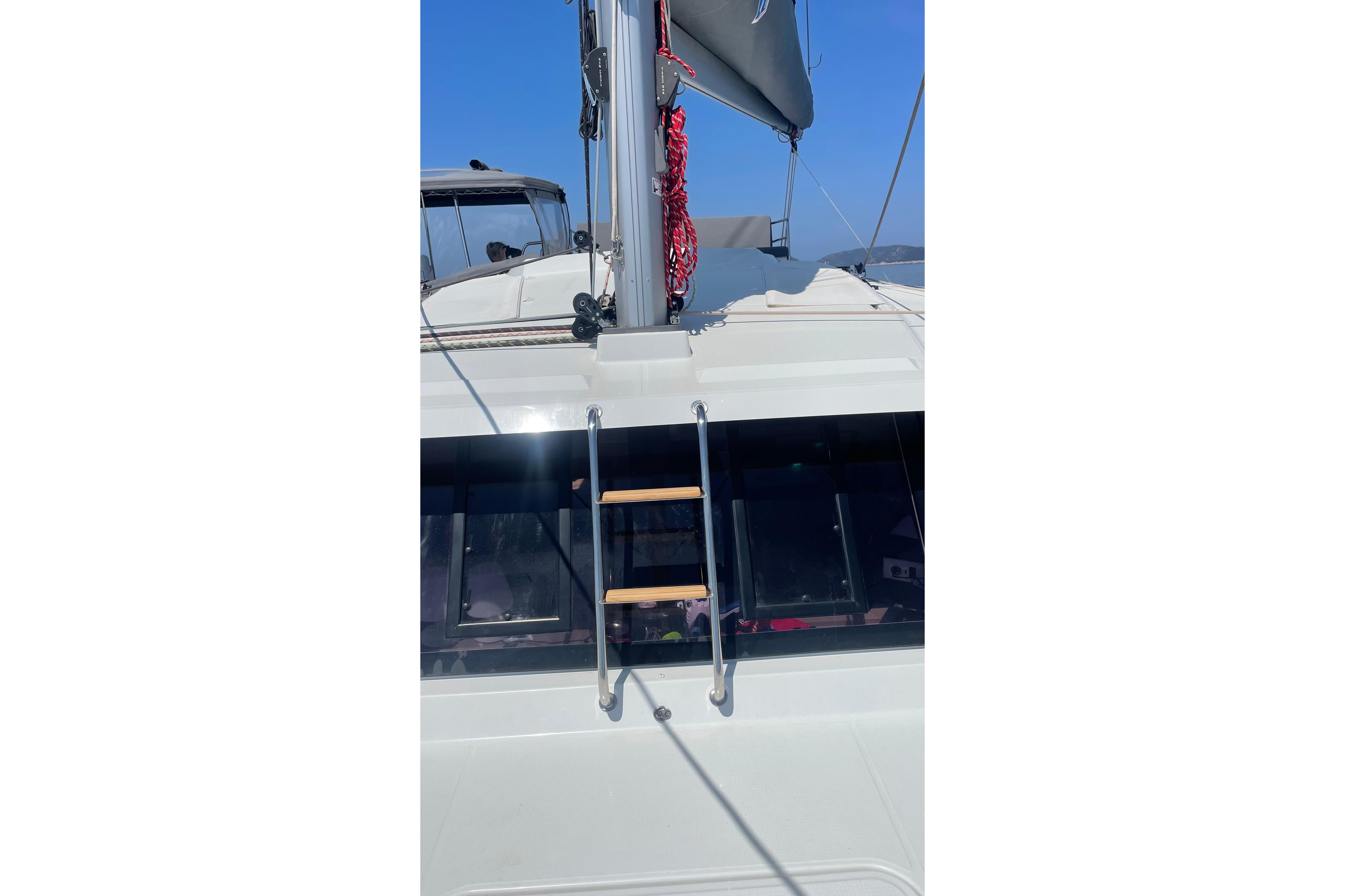 2020 Fountaine Pajot Saona 47 catamaran deck with ladder and mast, under clear blue sky.