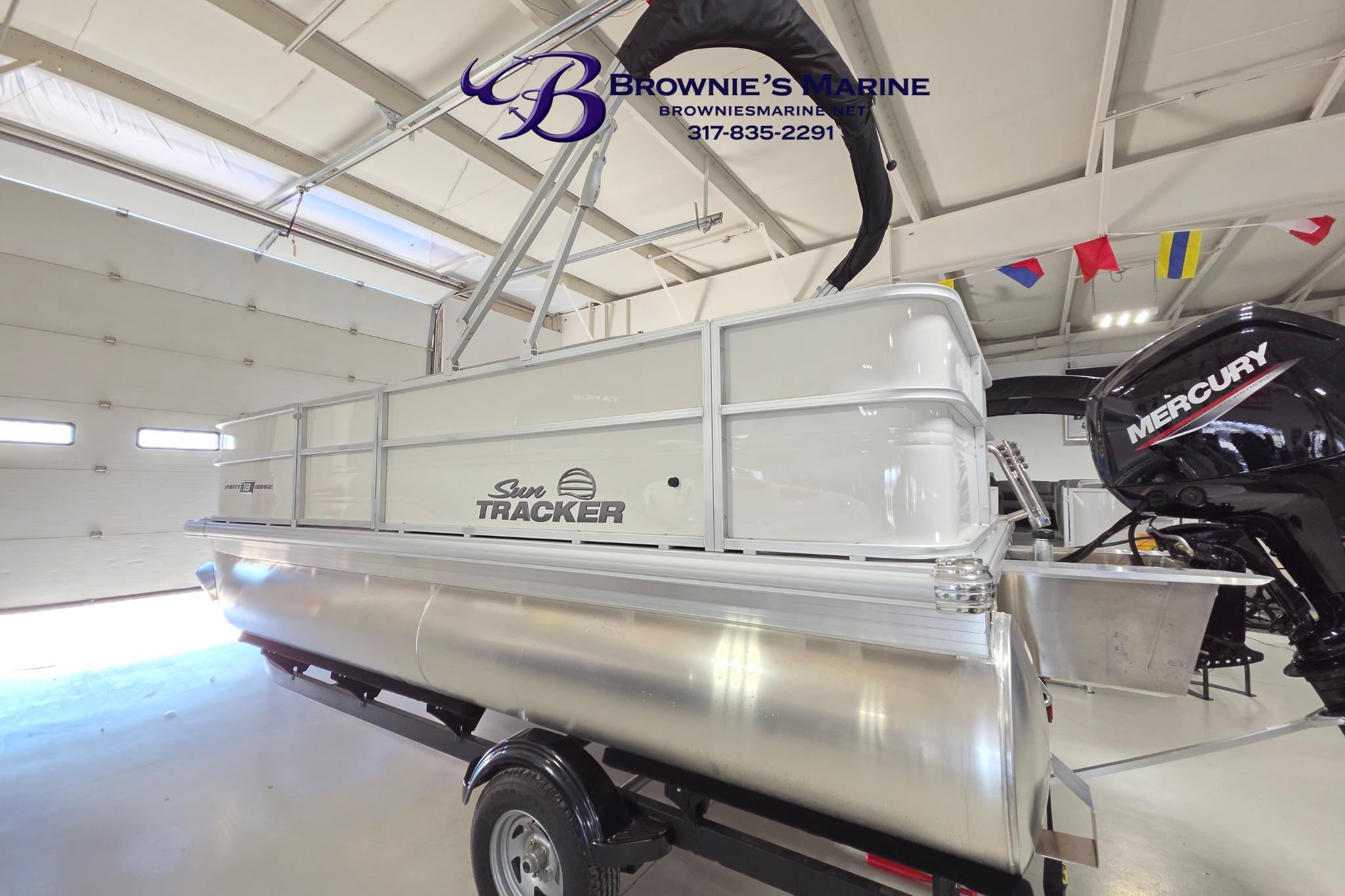 2026 Sun Tracker Party Barge 18 DLX pontoon boat in showroom with Mercury engine.