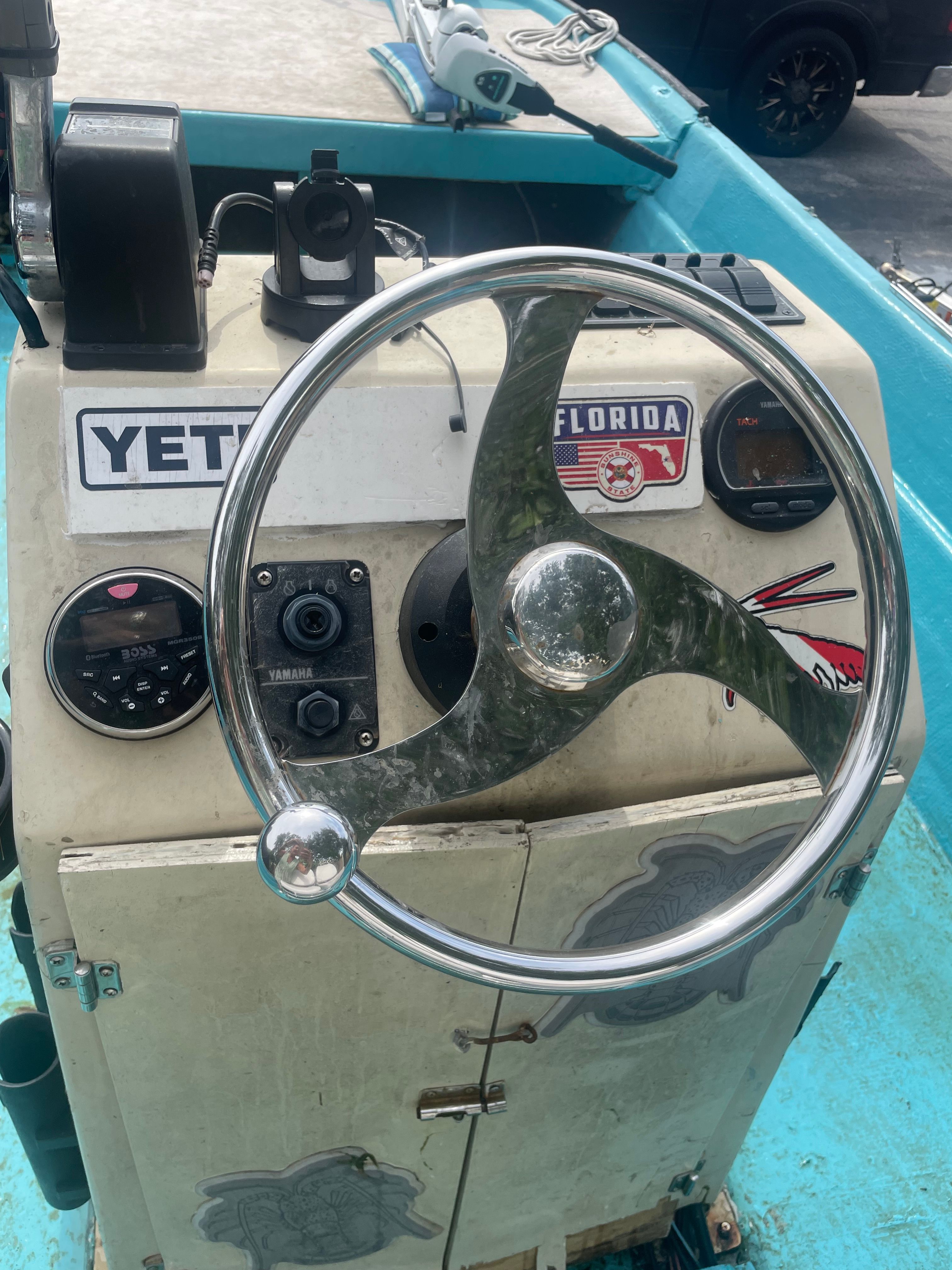 Boat helm with a shiny steering wheel and stickers.