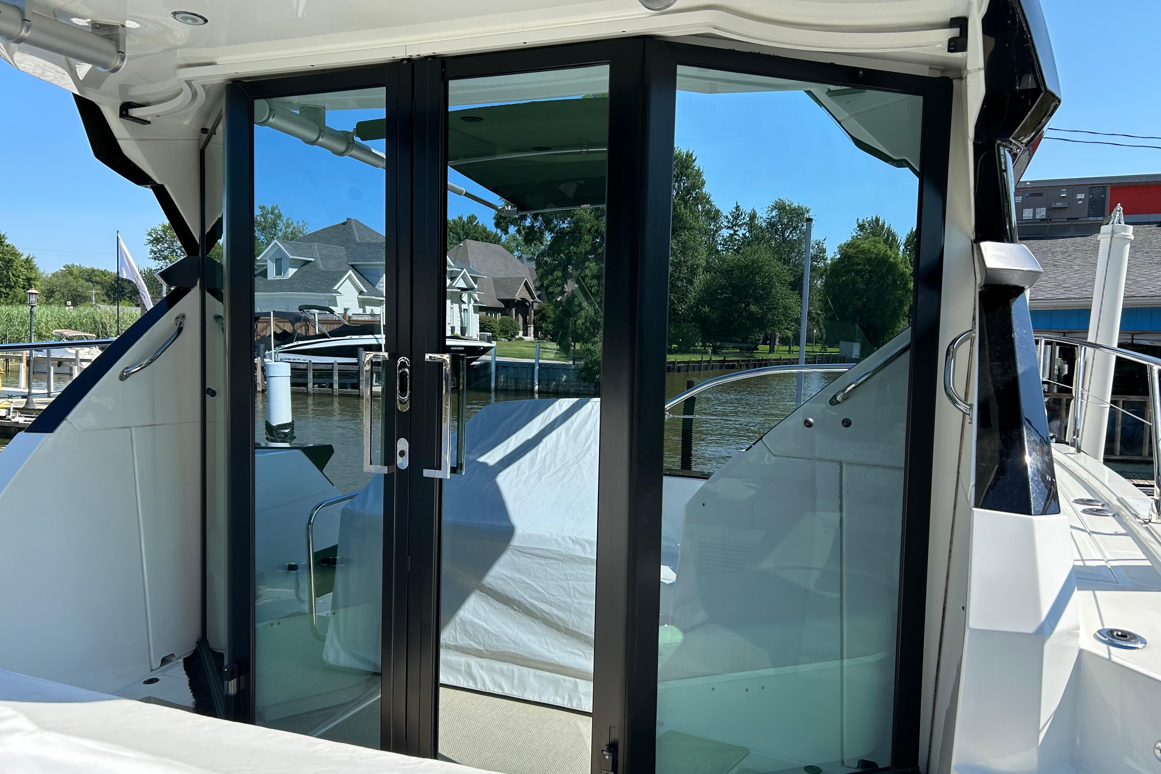 2019 Beneteau Gran Turismo 46 yacht with glass doors, docked near waterfront homes.