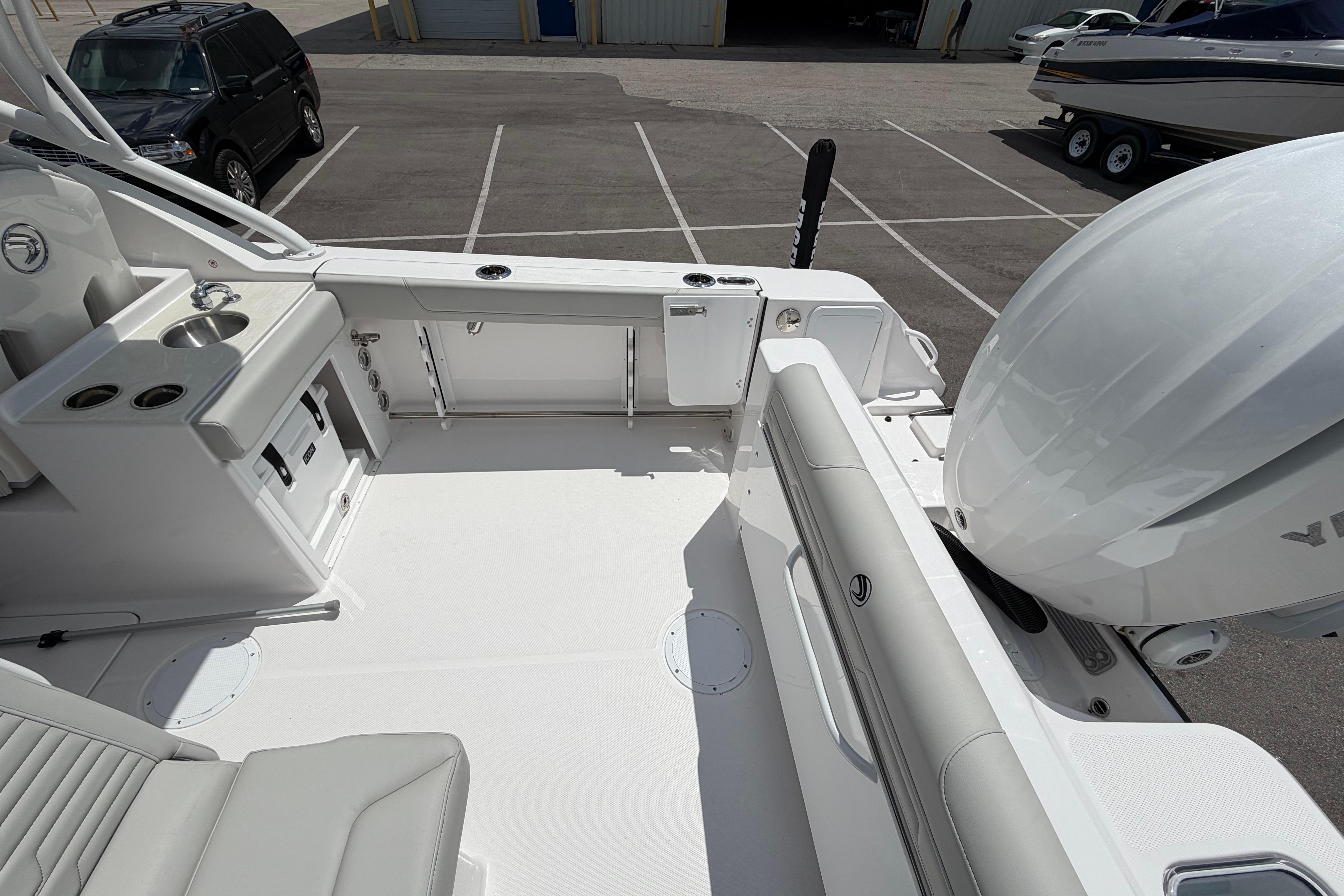 2026 Edgewater 248CX Crossover boat interior with seating and outboard motor in parking lot.
