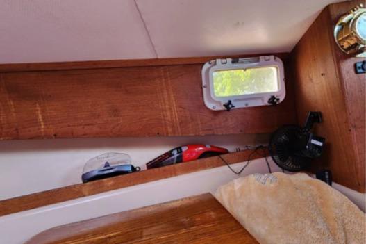 Interior of 1985 Wasque Down East Cruiser with wooden shelves and small window.