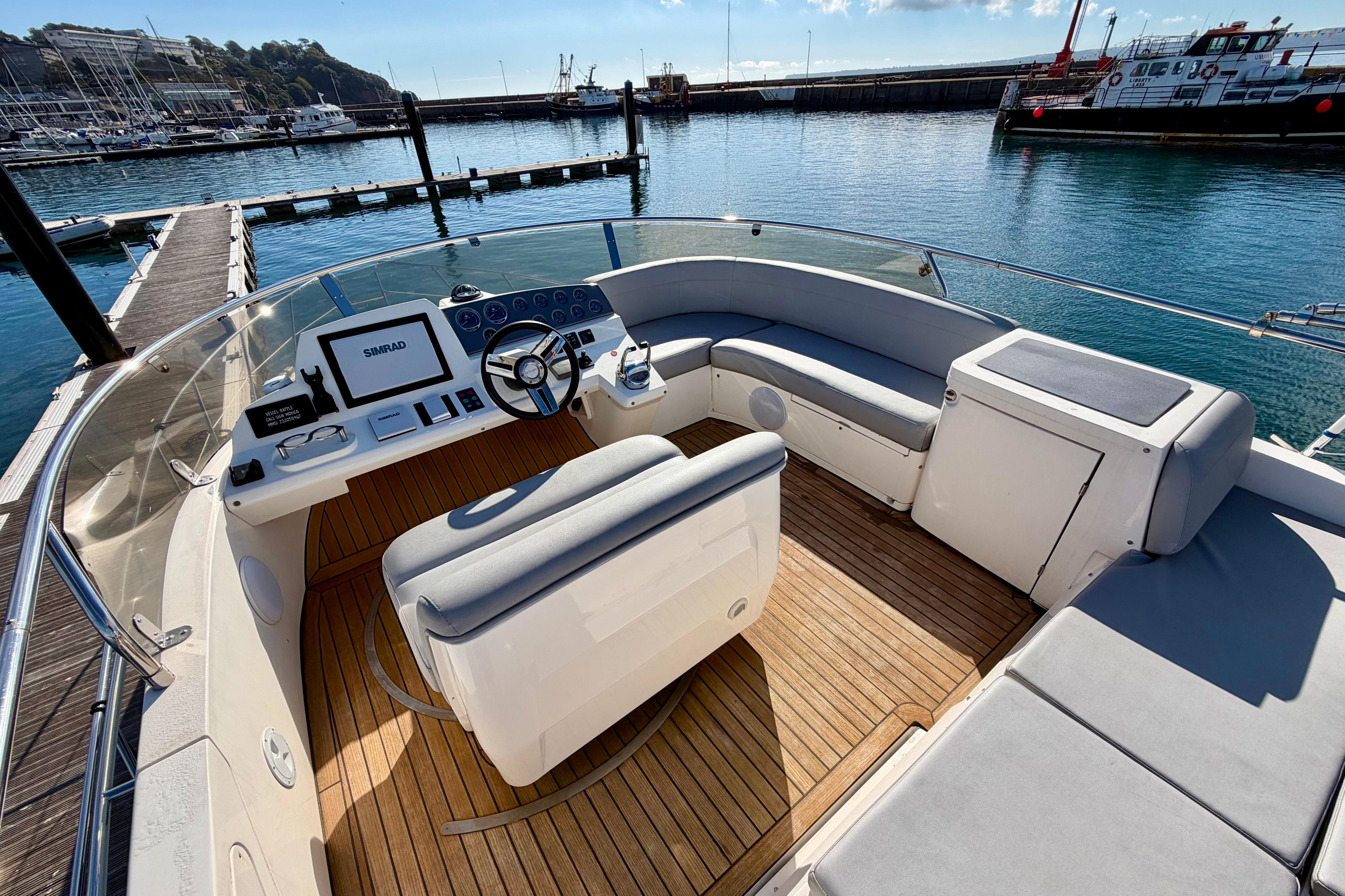 2009 Sealine F42/5 yacht helm with modern controls and spacious seating at marina.