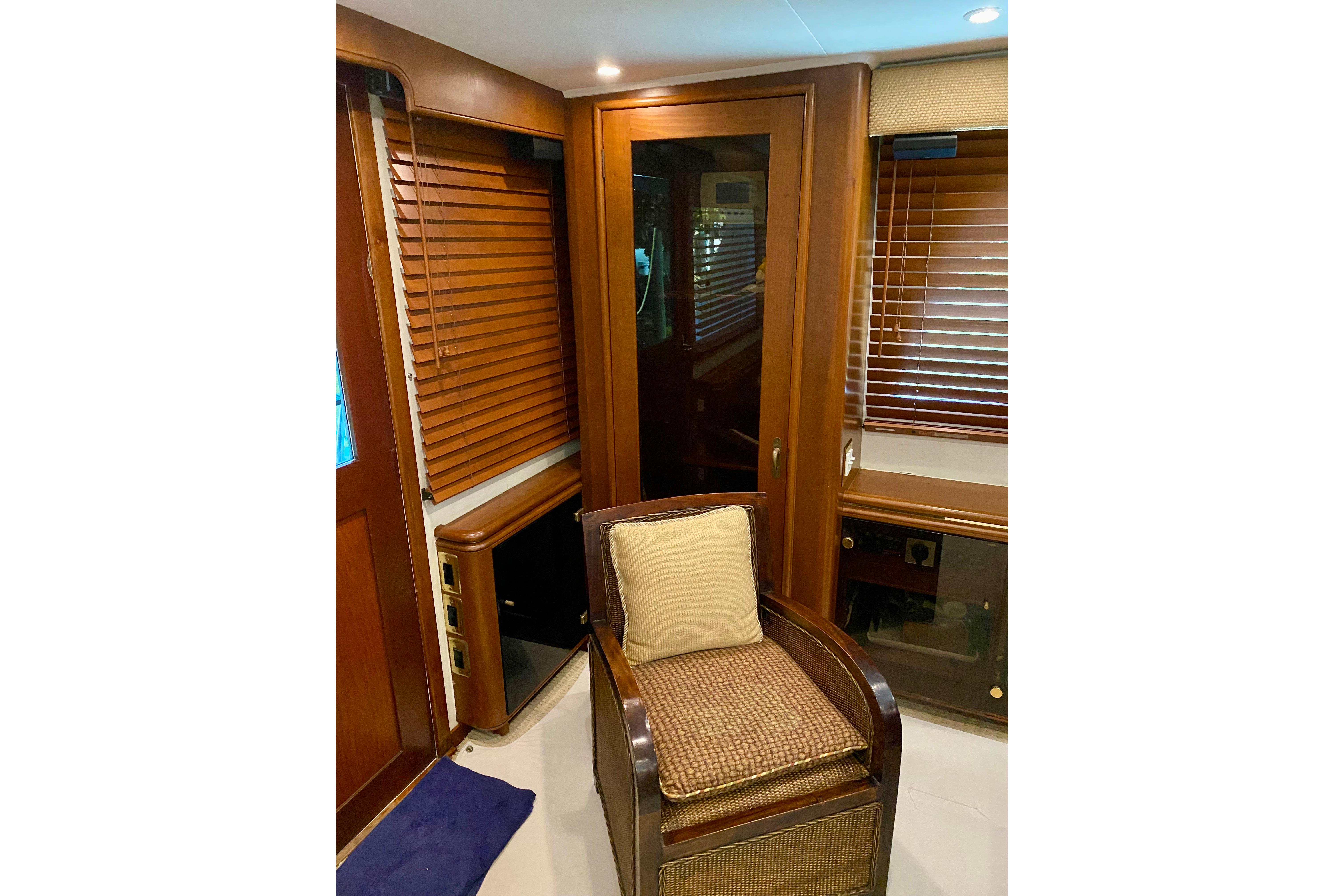 1986 Huckins Sport Fisherman interior with wooden blinds and wicker chair.