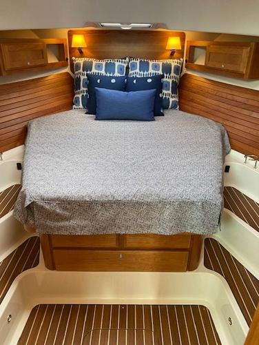 Luxurious cabin interior of 2025 Back Cove 39O with cozy bed and wooden accents.