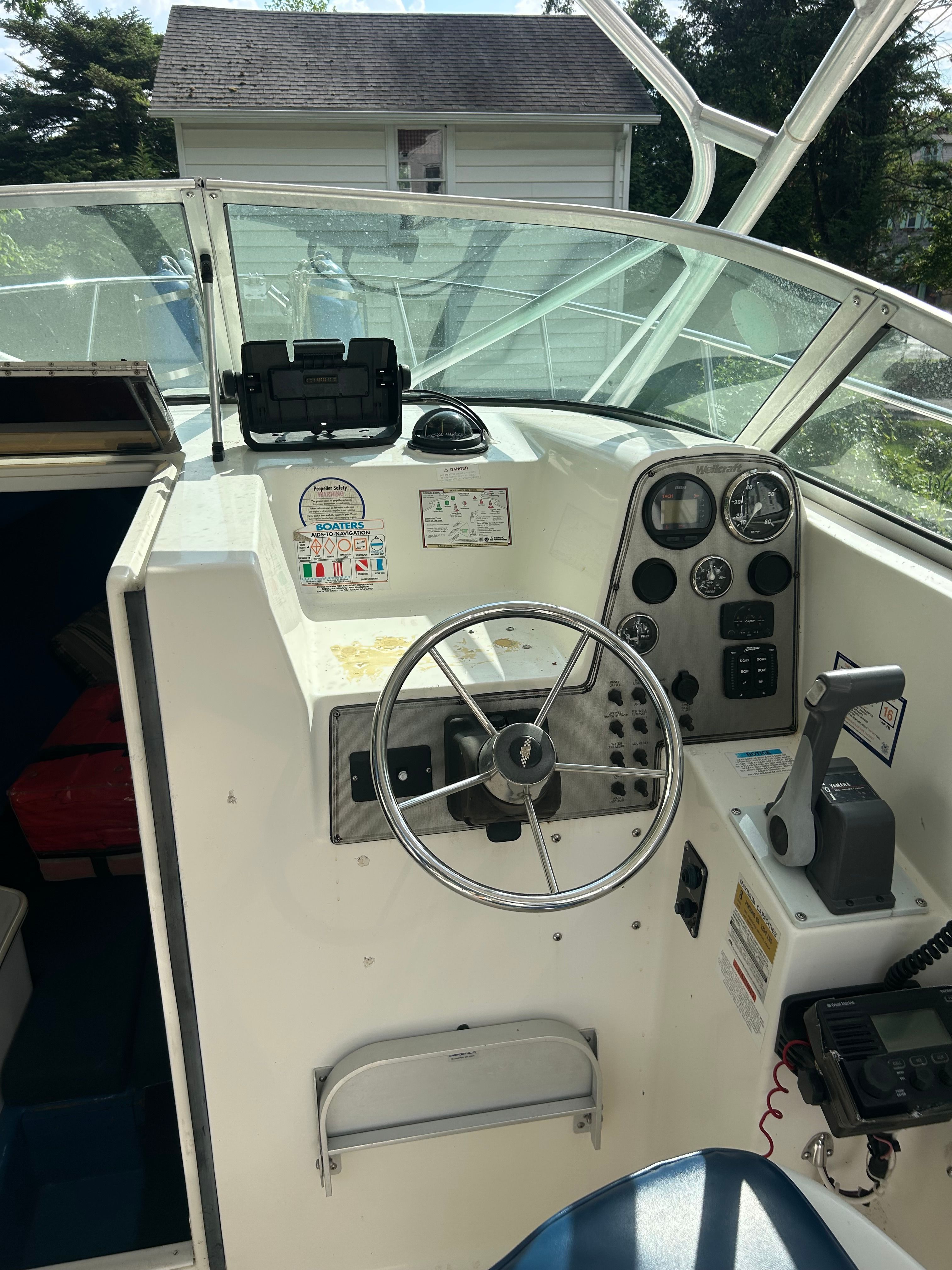 The image shows the helm of a 2002 Wellcraft 24 Walkaround boat with steering wheel and instruments.