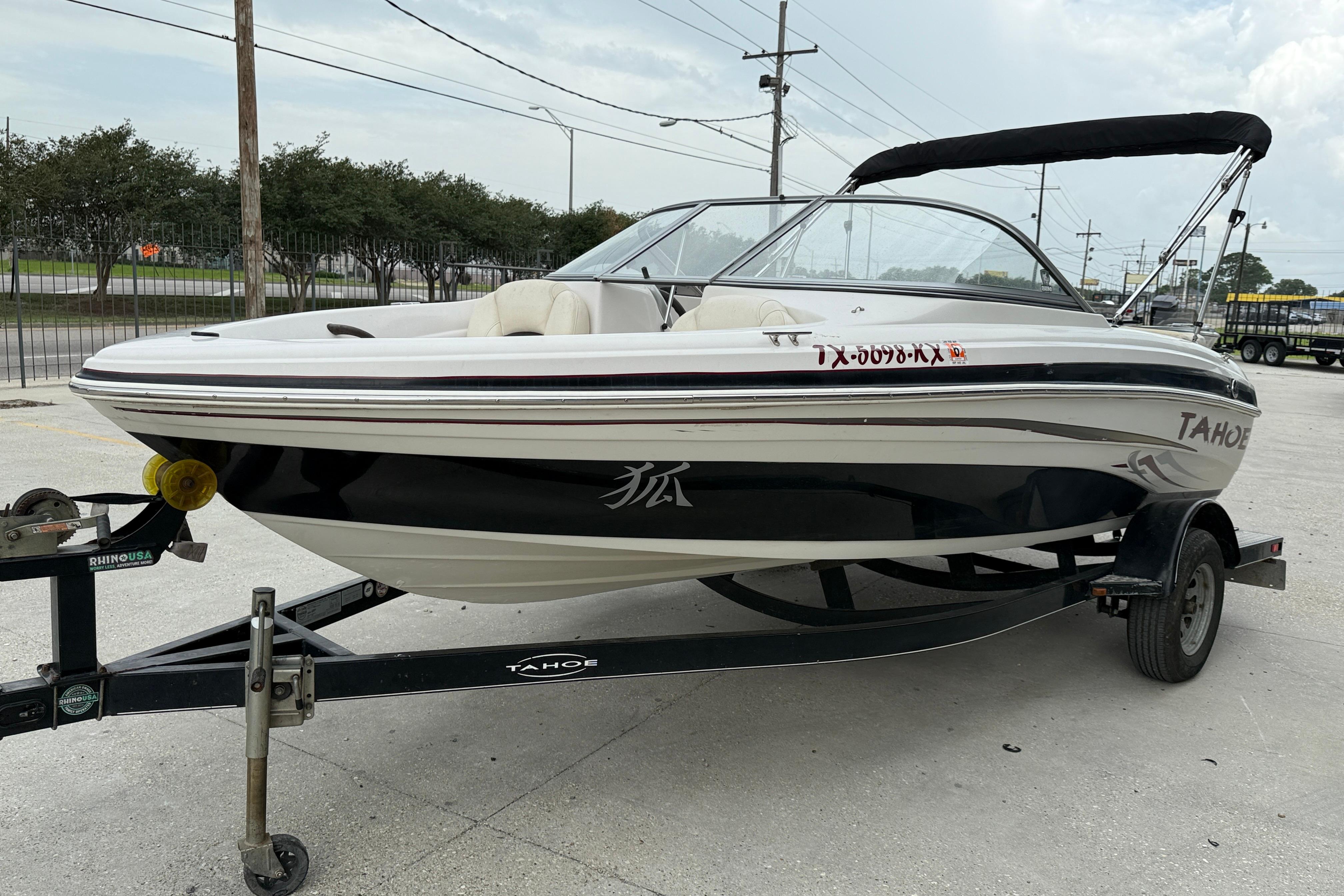2010 Tahoe Q4 boat on trailer, parked outdoors, with canopy and sleek design.