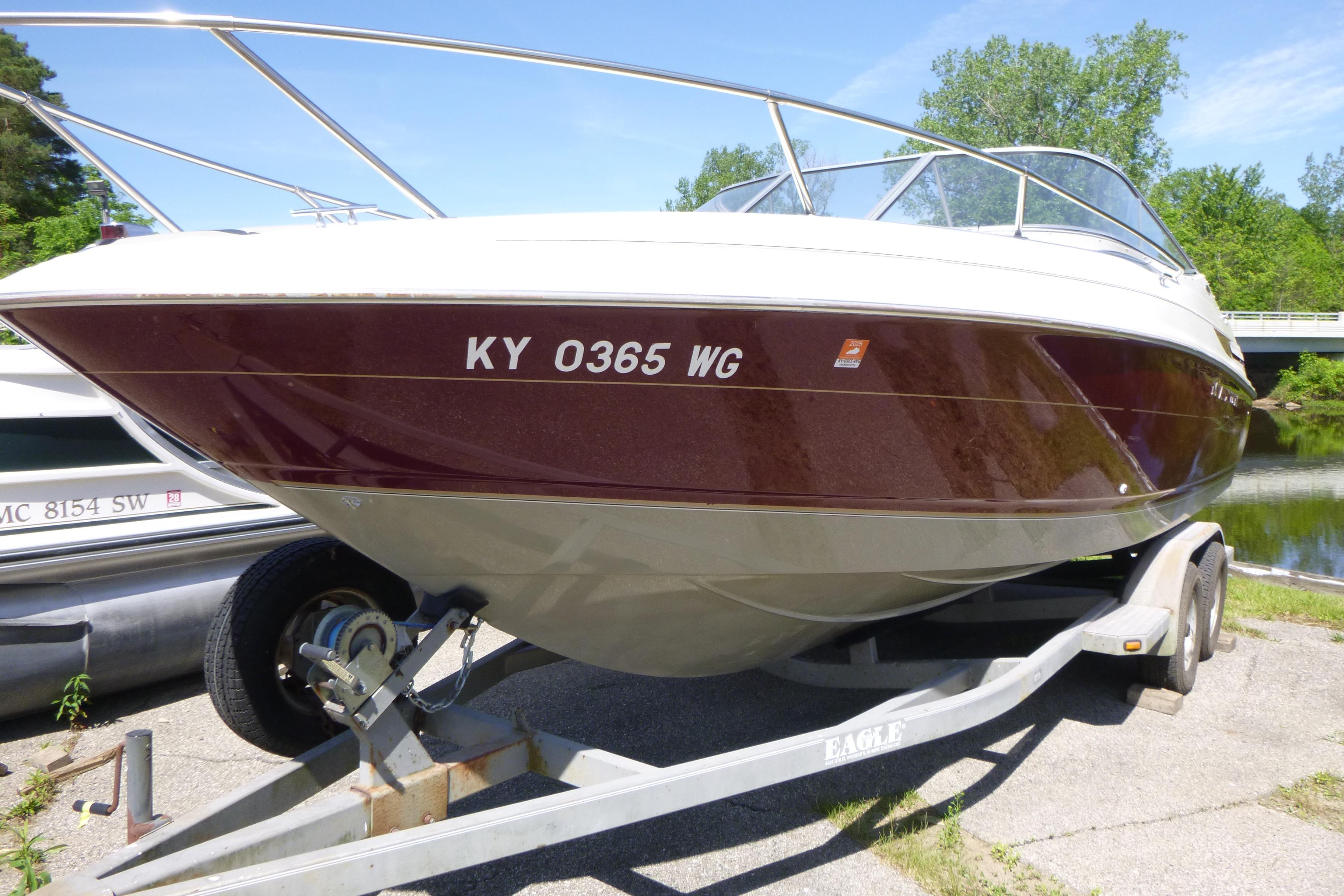 1998 Maxum 2300 SC boat on trailer, parked near a scenic waterway.