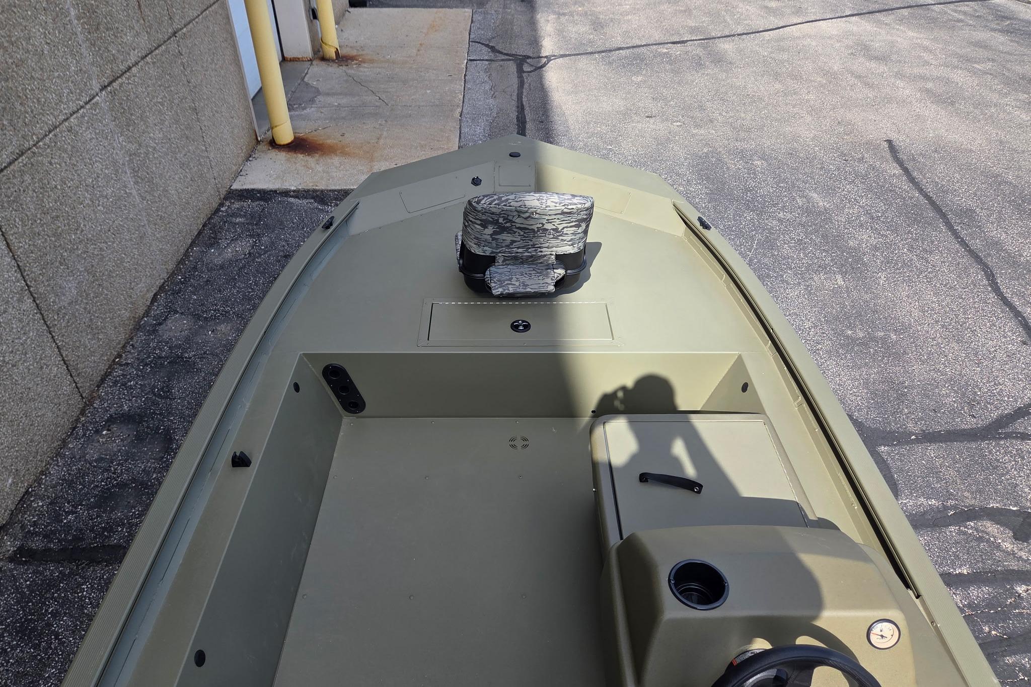 2026 Tracker Grizzly 1754 SC boat, olive green, parked on pavement near a building.
