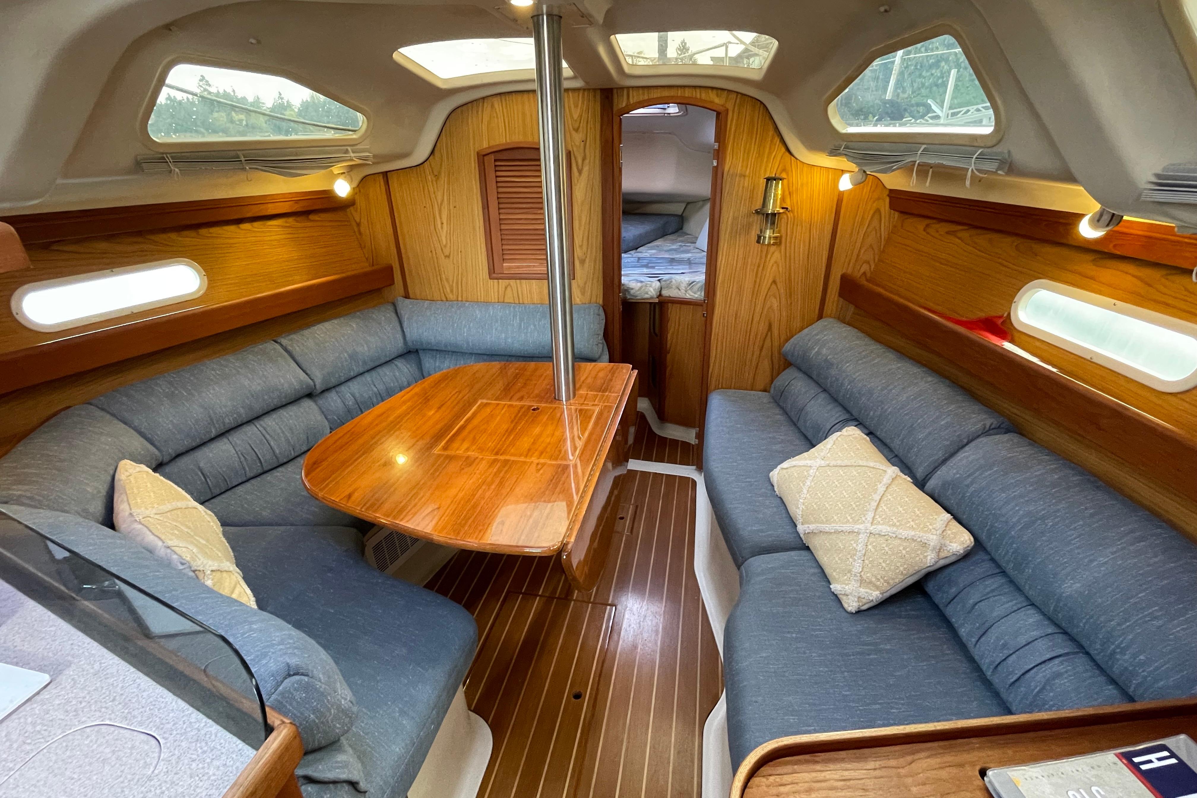 Interior of a 2000 Hunter 340 sailboat with cozy seating and wooden accents.