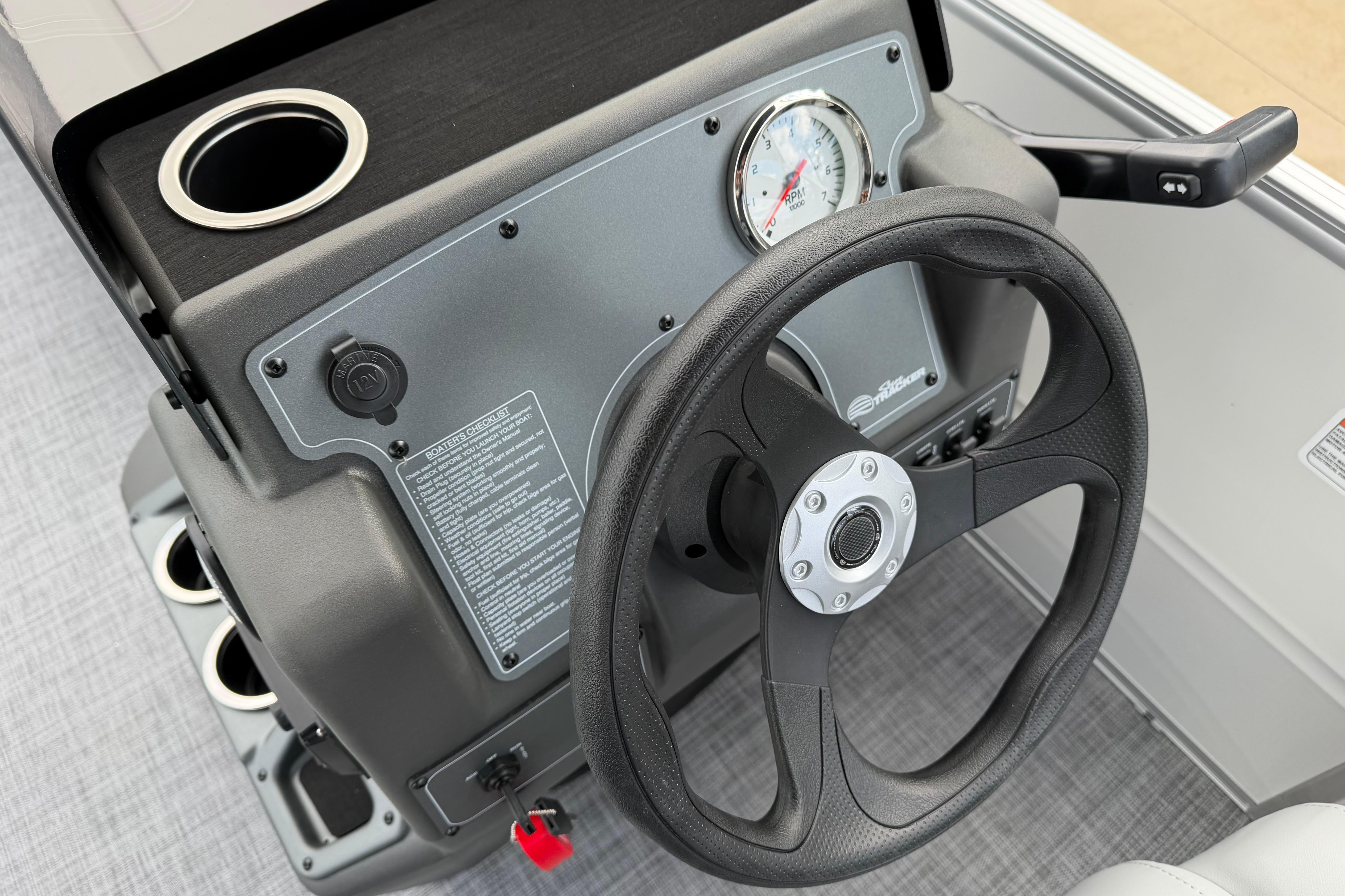 Steering console of 2026 Sun Tracker Party Barge 16 DLX with cup holder and gauge.