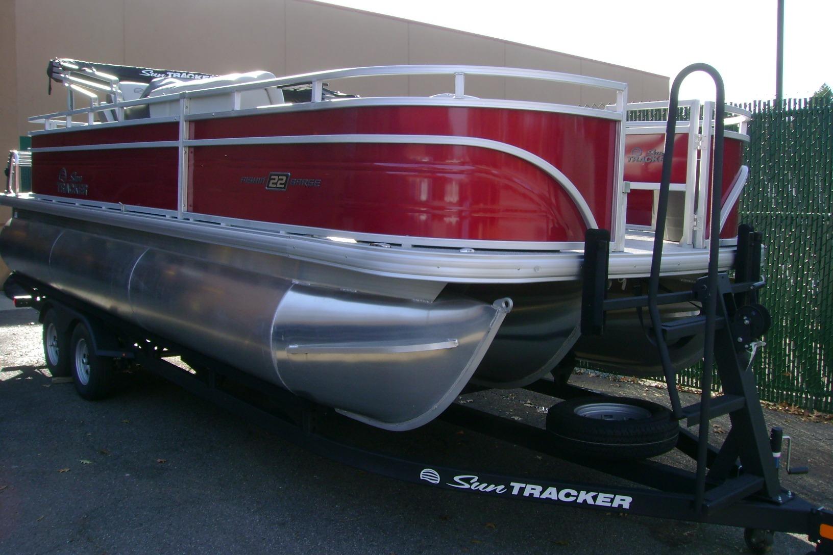 2026 Sun Tracker Fishin' Barge 22 XP3 pontoon boat on trailer, red and silver design.