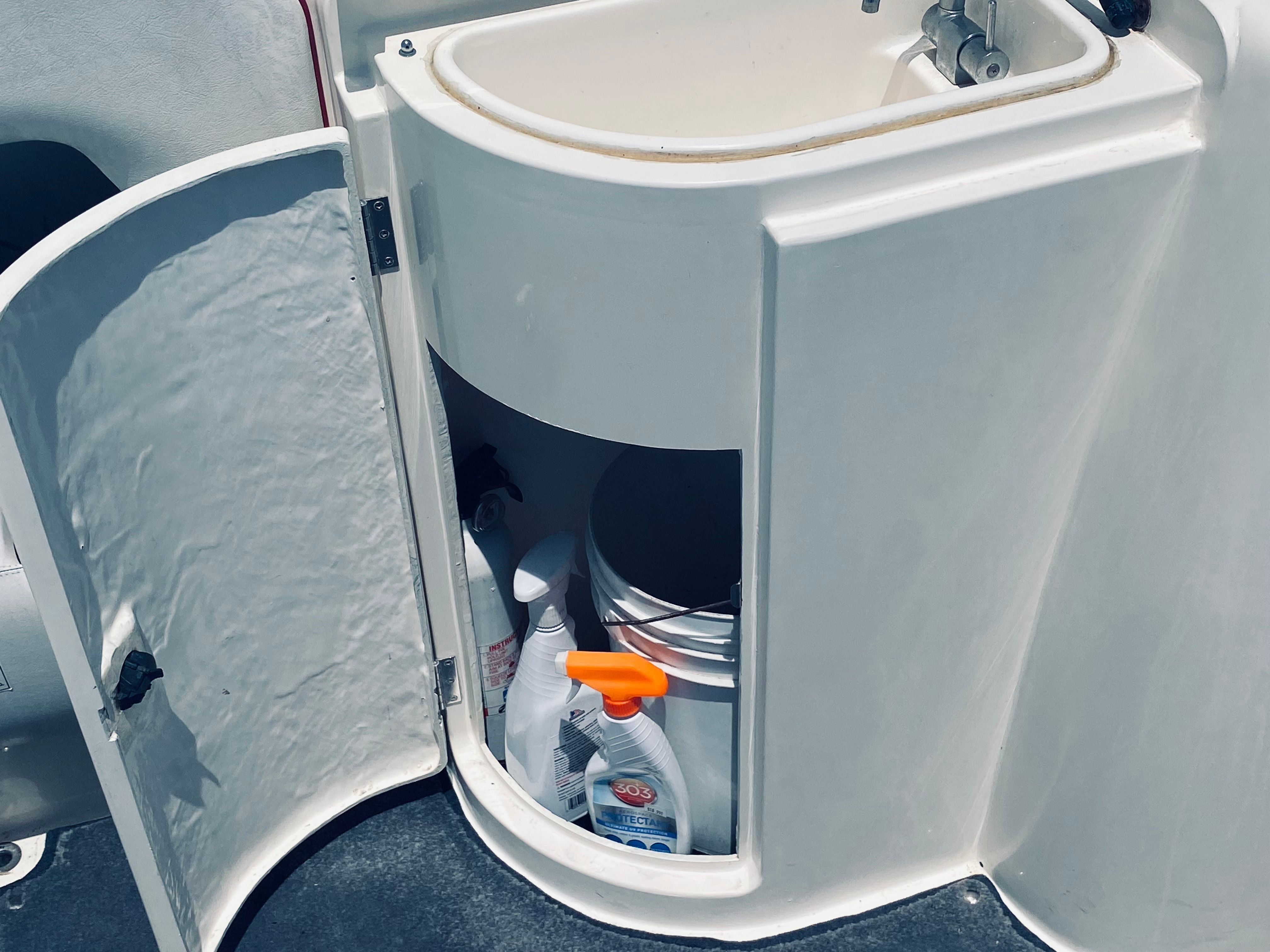 Open storage compartment on Sunseeker Hawk 31 boat, cleaning supplies visible.