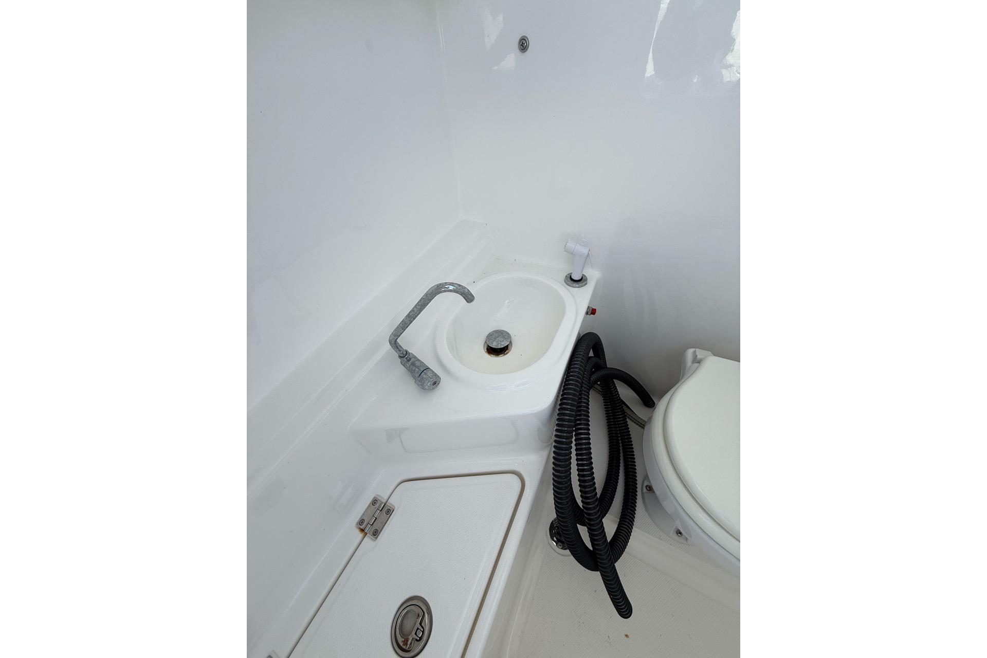Boat bathroom with sink, faucet, and coiled hose on Custom Infusion 34 CC, 2021 model.