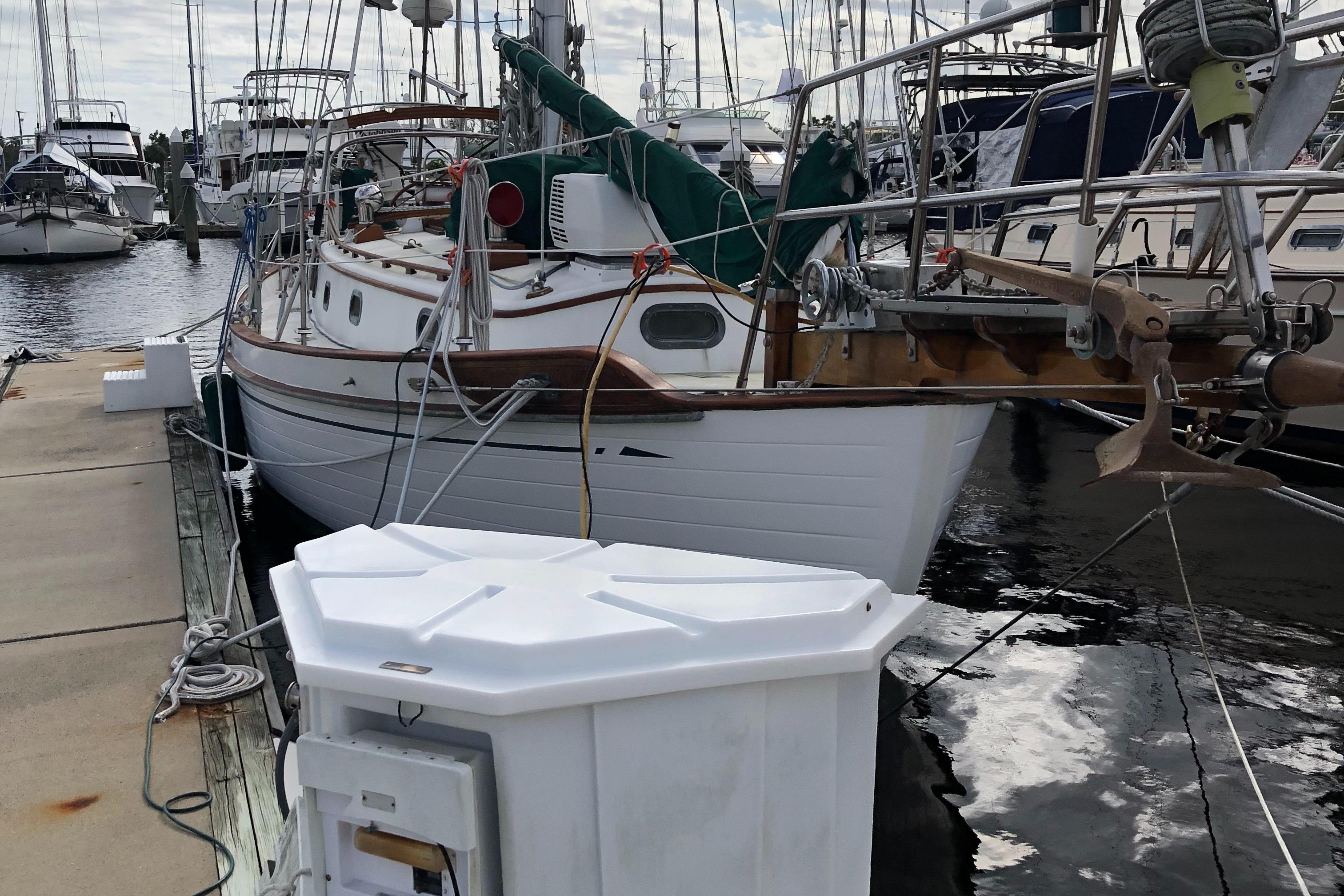 1985 Tayana 37 sailboat docked at marina, surrounded by other boats.