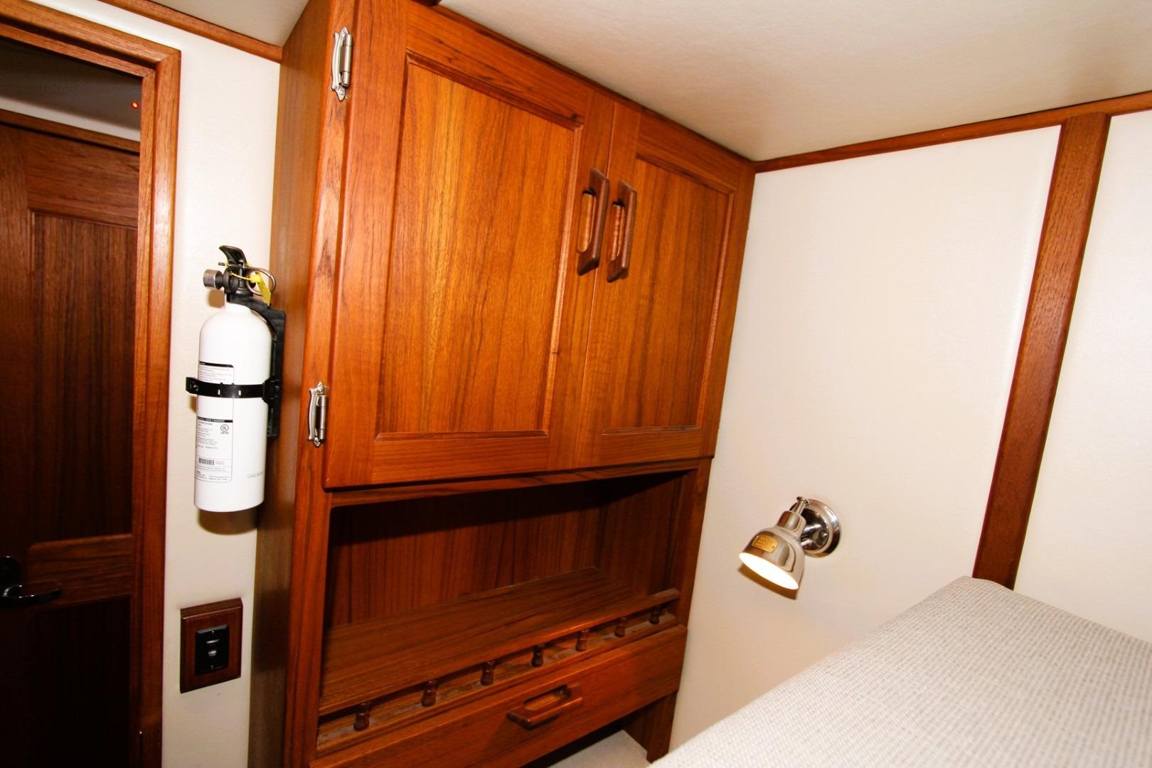 Wooden interior of 2002 Nordic Tug 37 with cabinets and fire extinguisher.