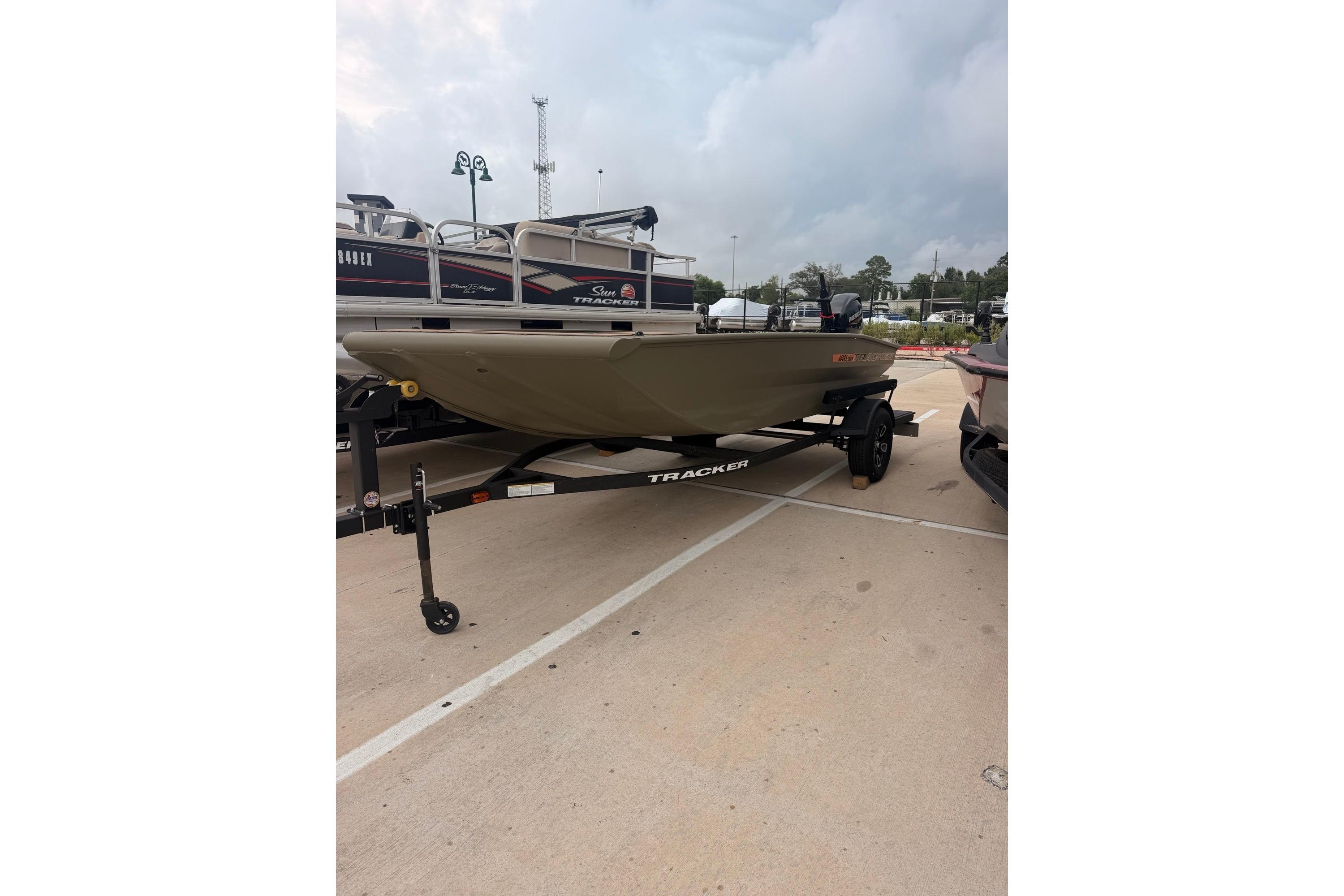 A Tracker Grizzly 1756 T Marsh boat on a trailer in a parking lot.