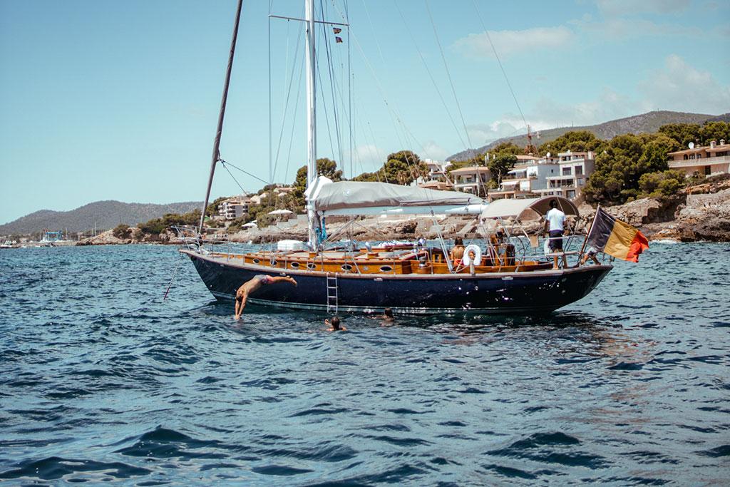 Sailing yacht Joubert-Nivelt TM 52, 2004, anchored near coastal homes, with people swimming nearby.