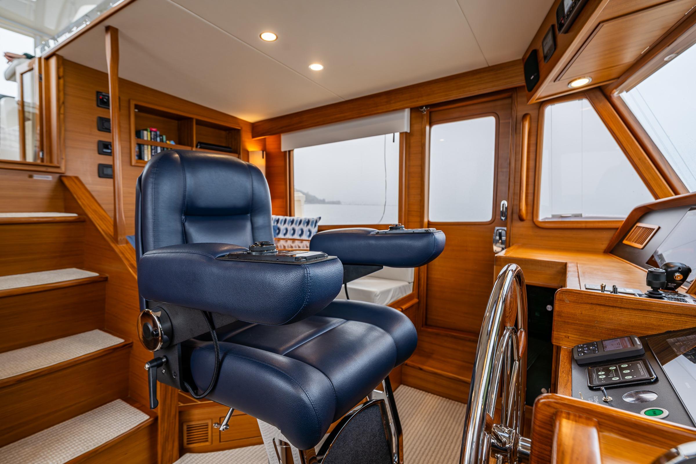 Luxurious 2026 Fleming 55 Pilothouse interior with blue captain's chair and wooden helm.