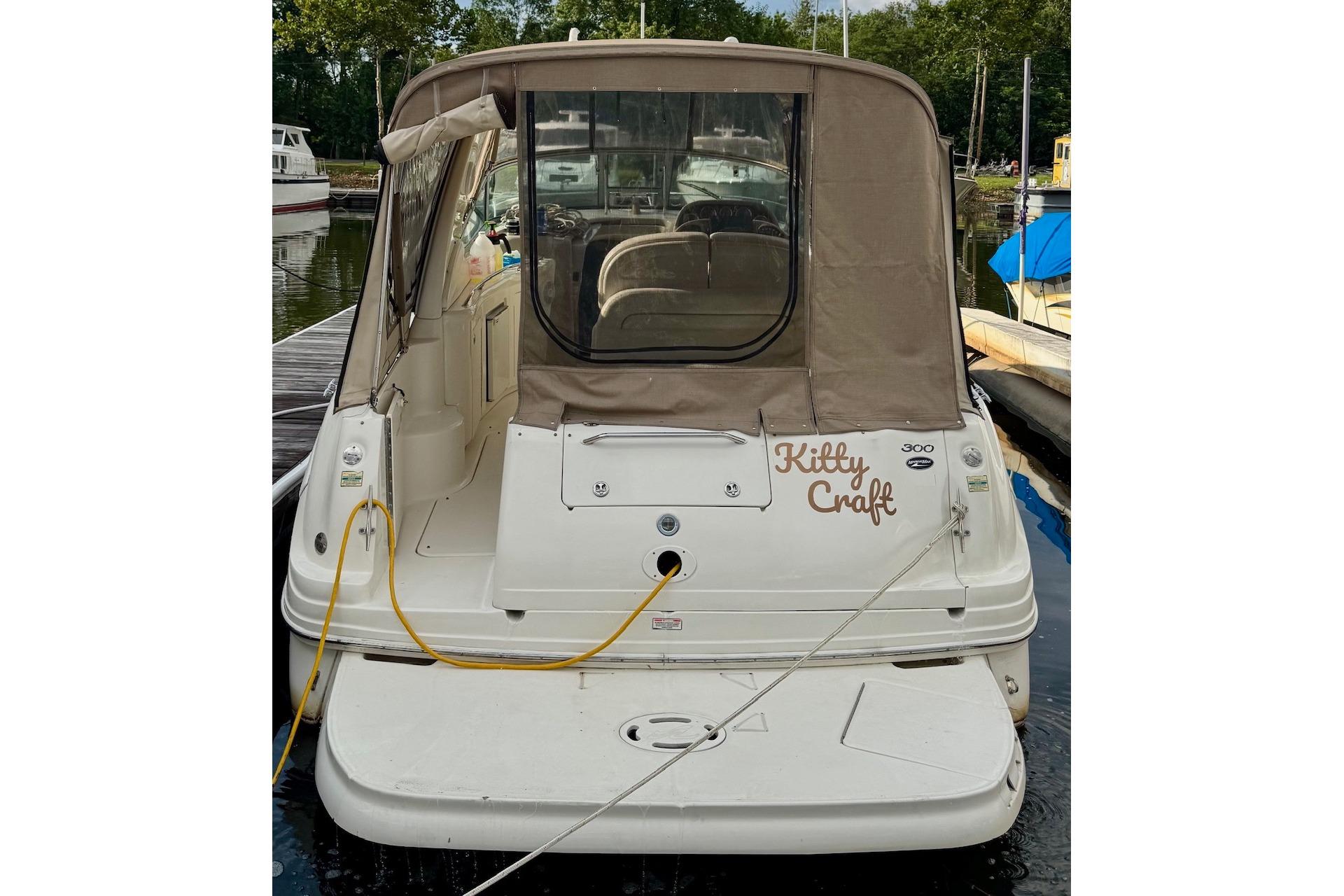 2003 Sea Ray 300 Sundancer boat docked, rear view with canopy and "Kitty Craft" text.