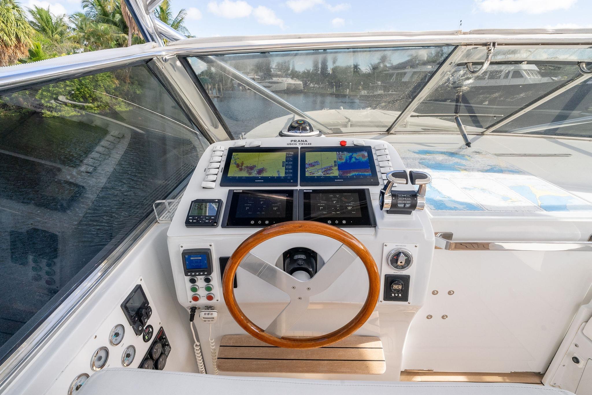 Cockpit of 1995 Itama 46 yacht with navigation screens and wooden steering wheel.
