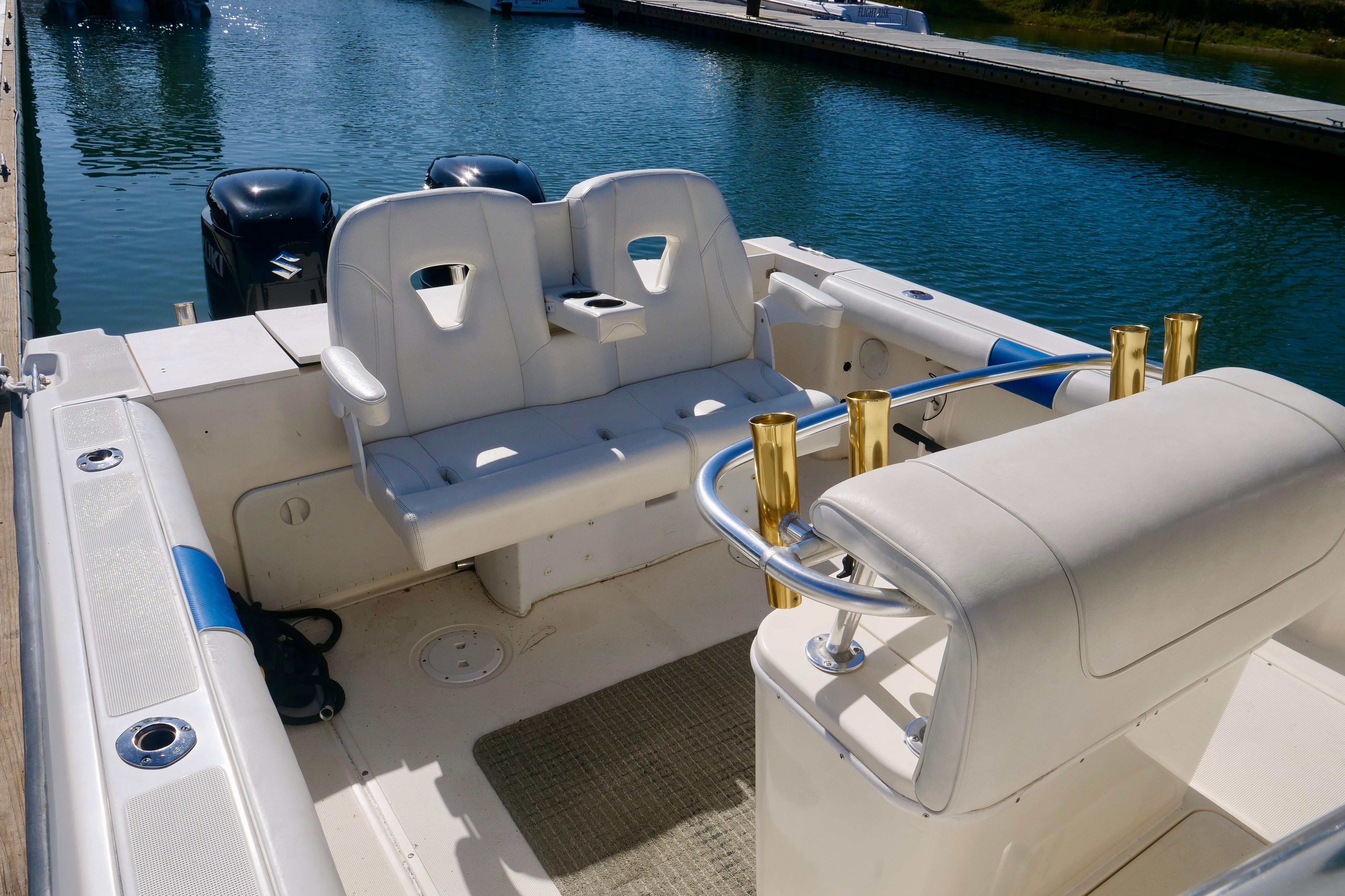 1999 Pursuit 2870 Walkaround boat interior with seating and rod holders at a marina.