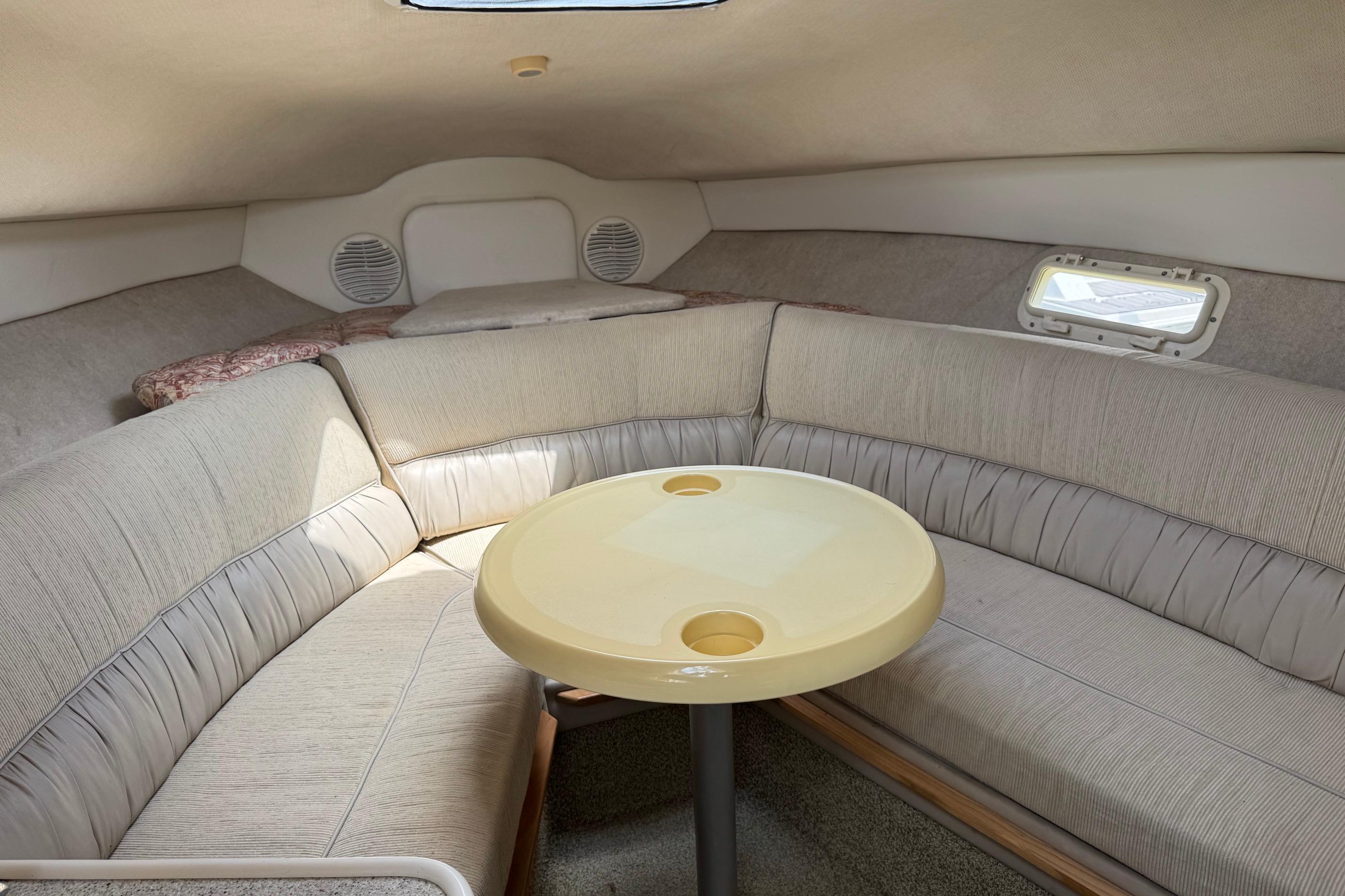 Cozy interior of 2000 Maxum 2400 SCR boat with cushioned seating and table.