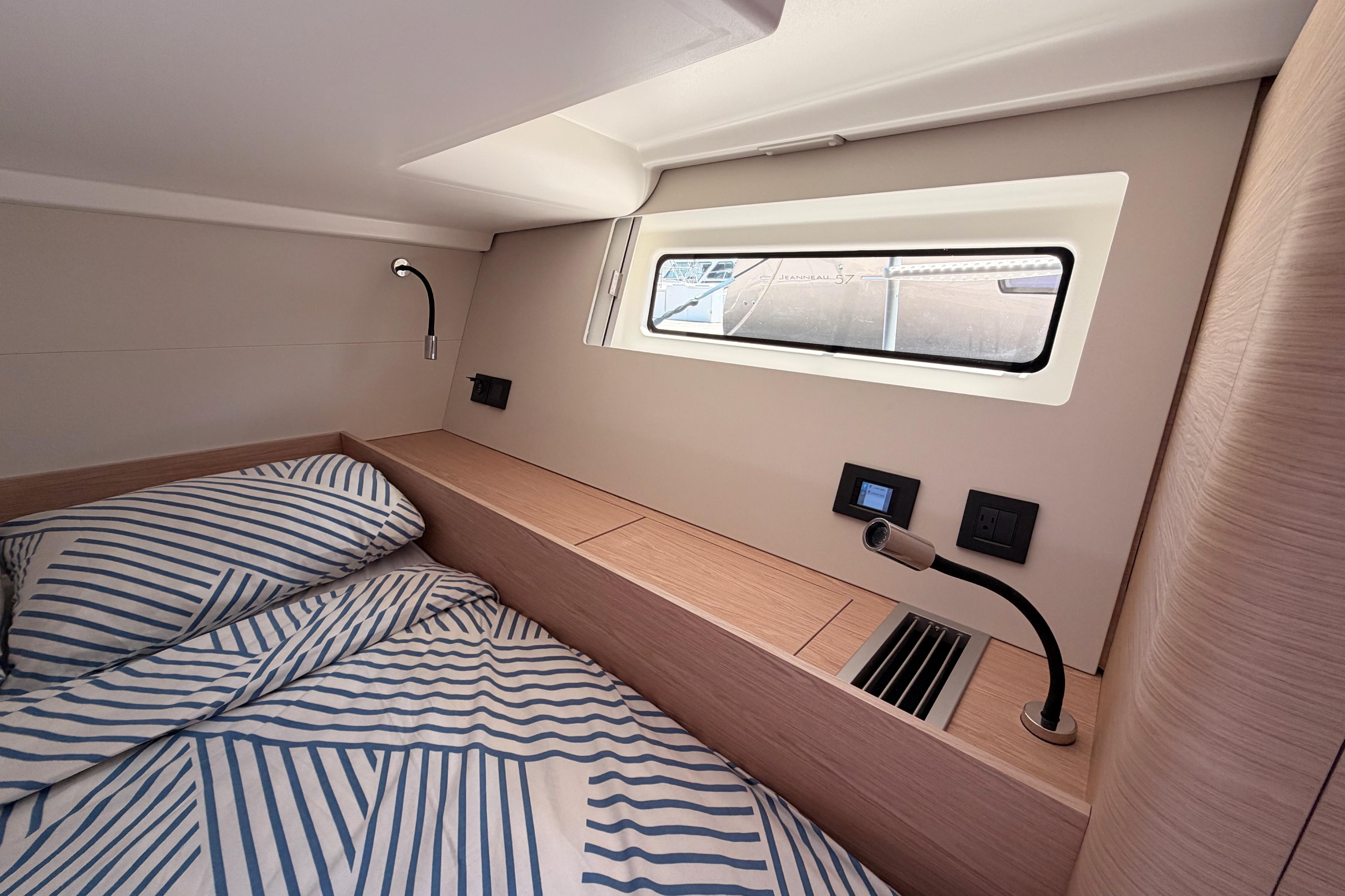 Luxurious cabin interior of 2022 Beneteau Oceanis Yacht 54 with striped bedding and modern fixtures.