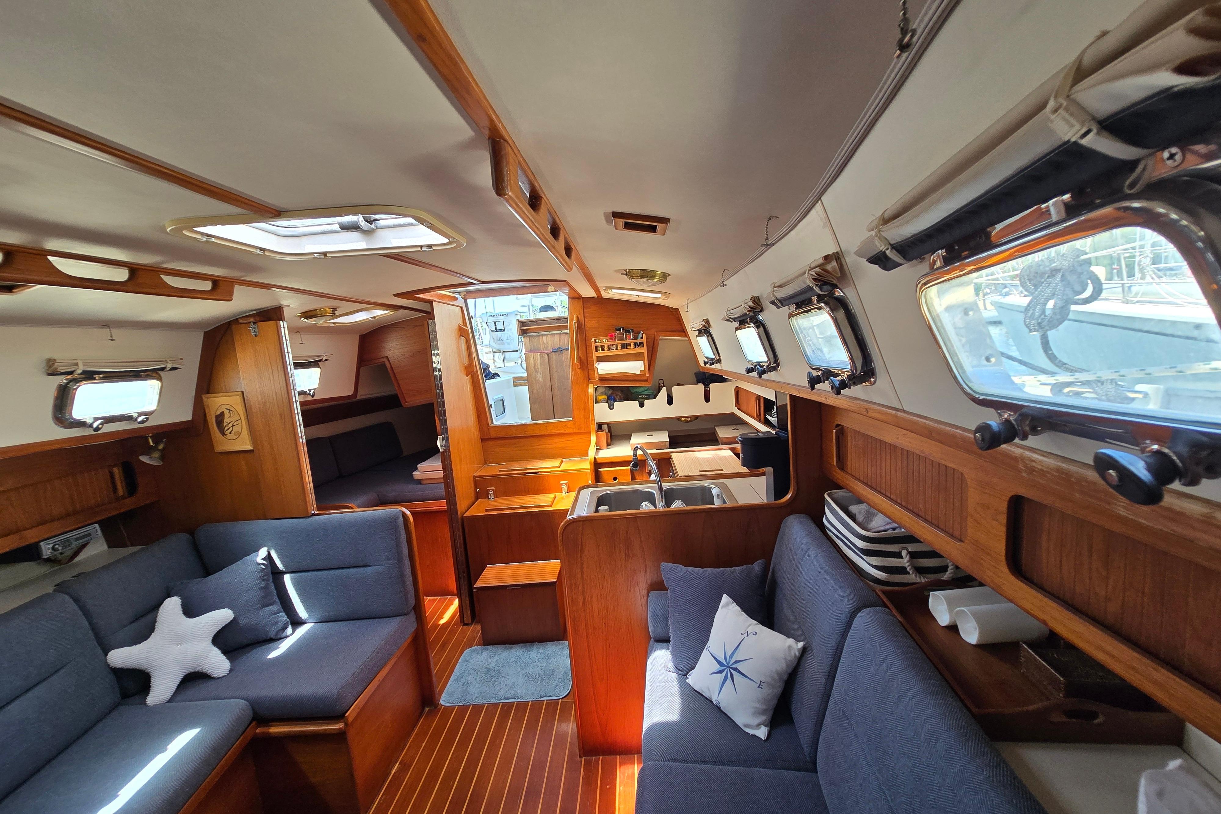 Interior of a 1993 Caliber 35 sailboat, featuring cozy seating and wooden accents.