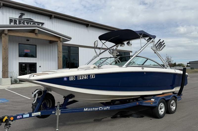 2004 MasterCraft XStar boat on trailer outside a building.