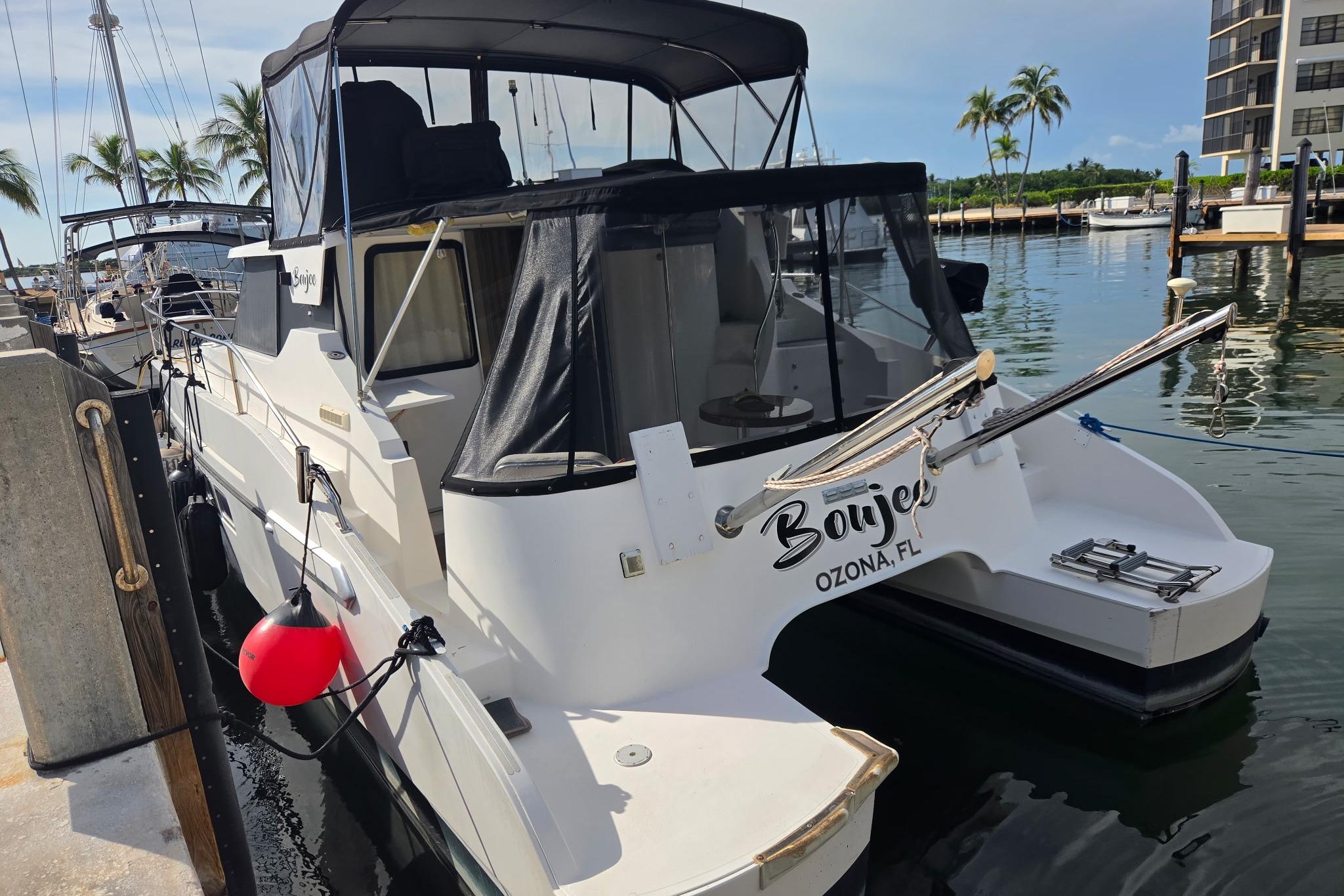 Fountaine Pajot Maryland 37 yacht docked in a marina, 2000 model, with palm trees nearby.