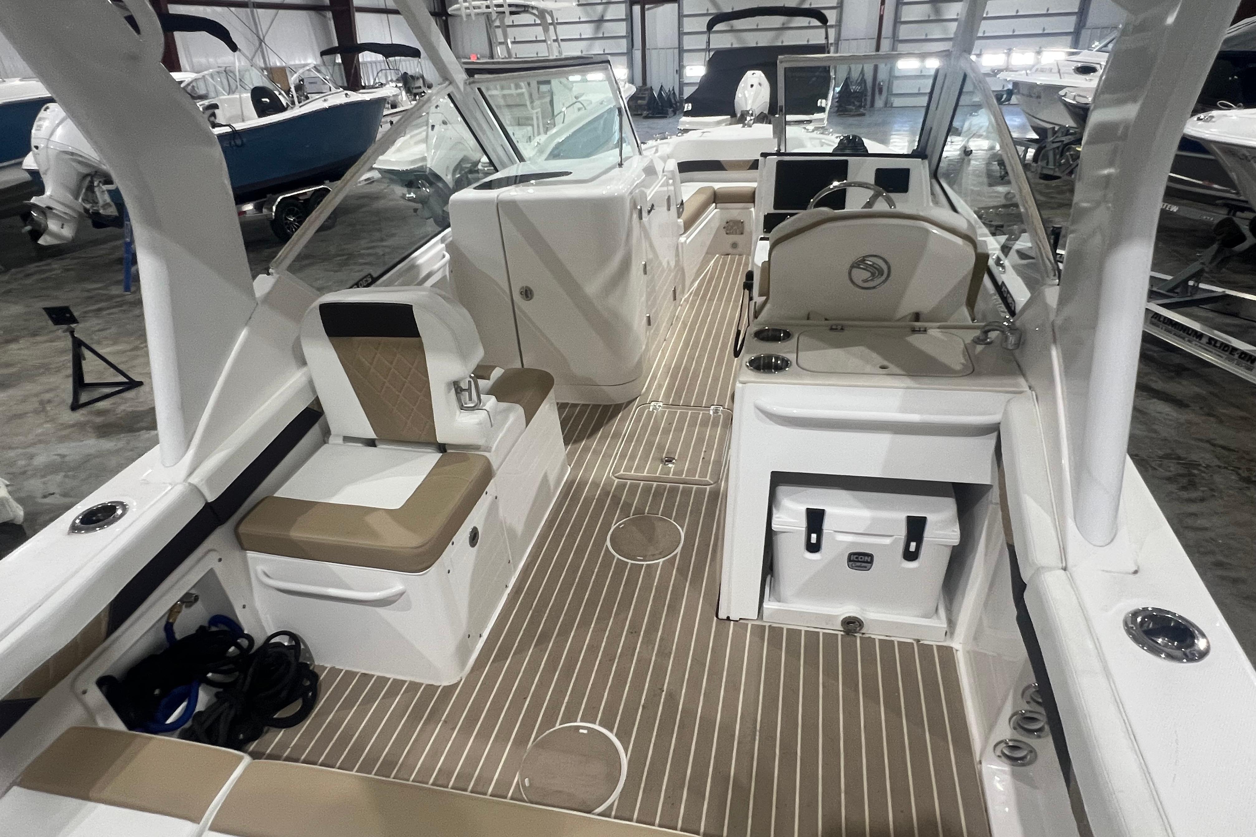 2023 Edgewater 230CX Crossover boat interior with seating and helm in a showroom.