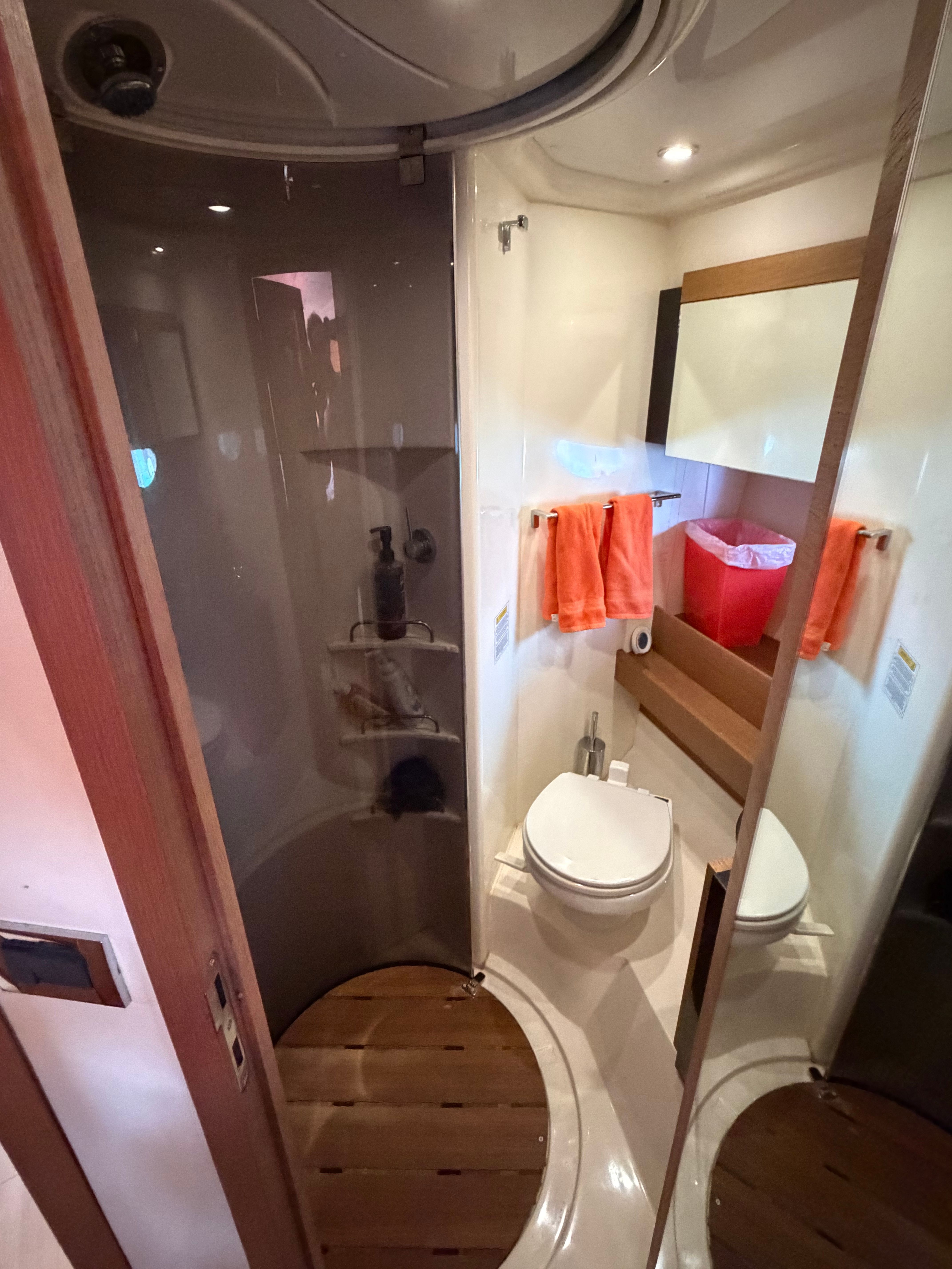The image shows a modern yacht bathroom with a toilet and shower.