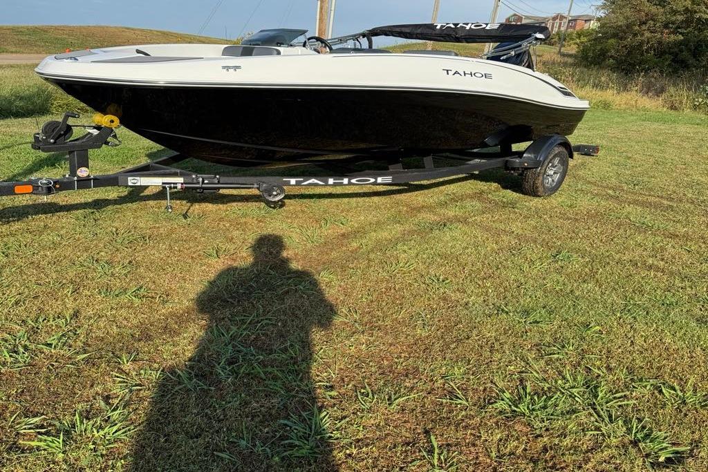 2026 Tahoe T16 boat on trailer, parked on grassy field under clear sky.