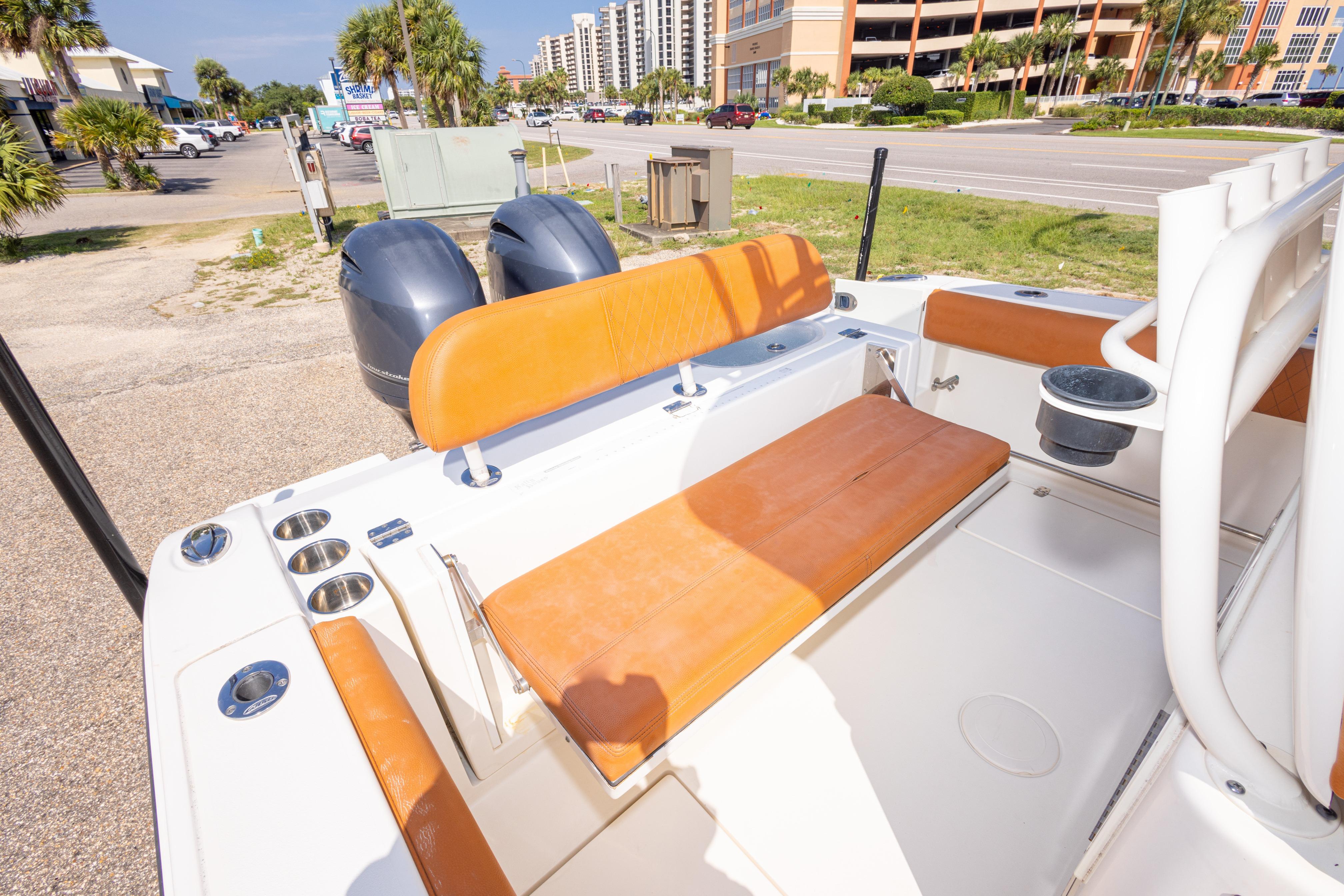 2017 Cobia 261 Center Console boat with orange seating and dual engines, parked near a road.
