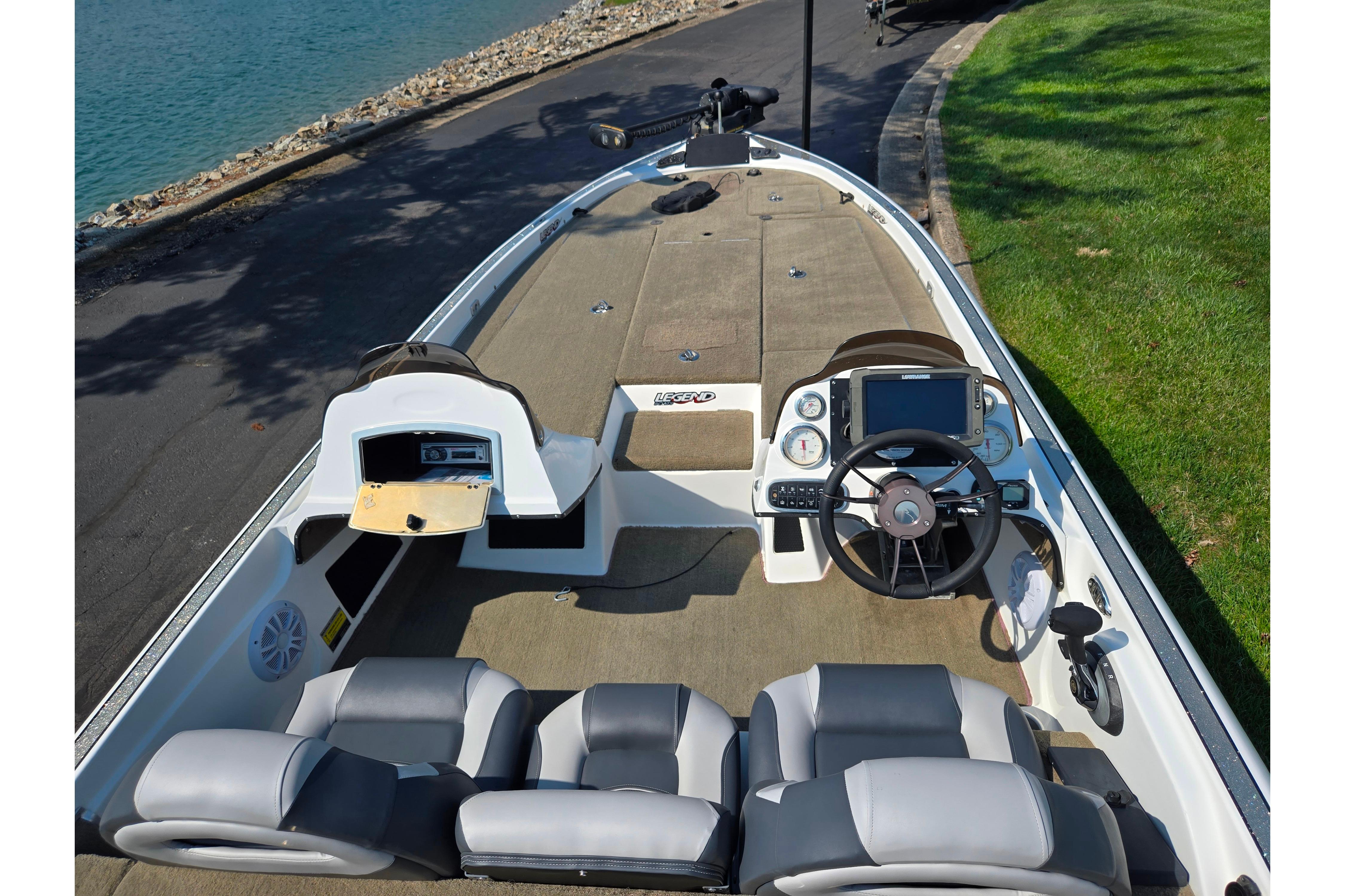 2016 Legend Alpha 211R DC boat interior with steering wheel and seating near a lakeside.