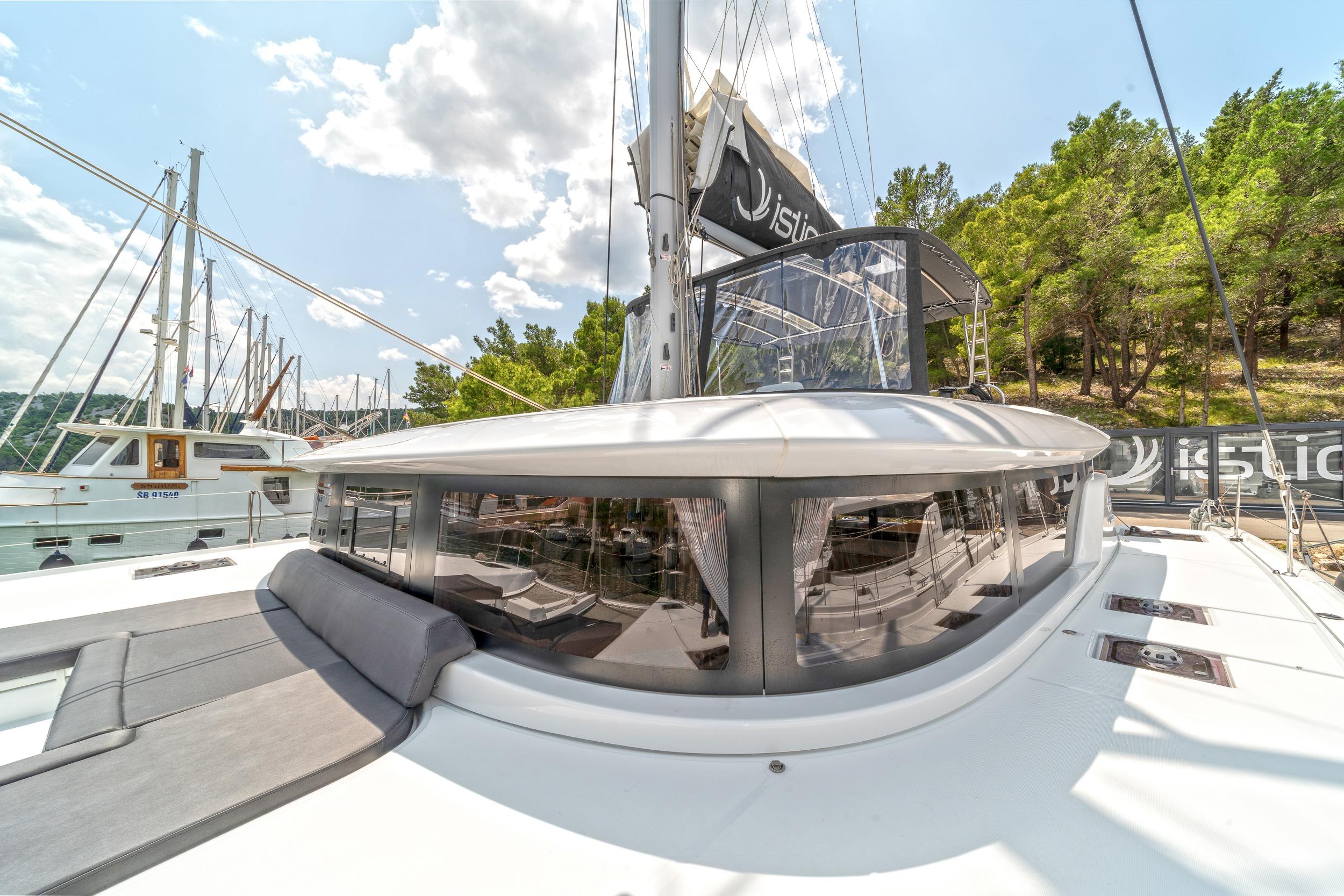 2023 Lagoon 46 catamaran docked, featuring sleek design and spacious deck under a sunny sky.