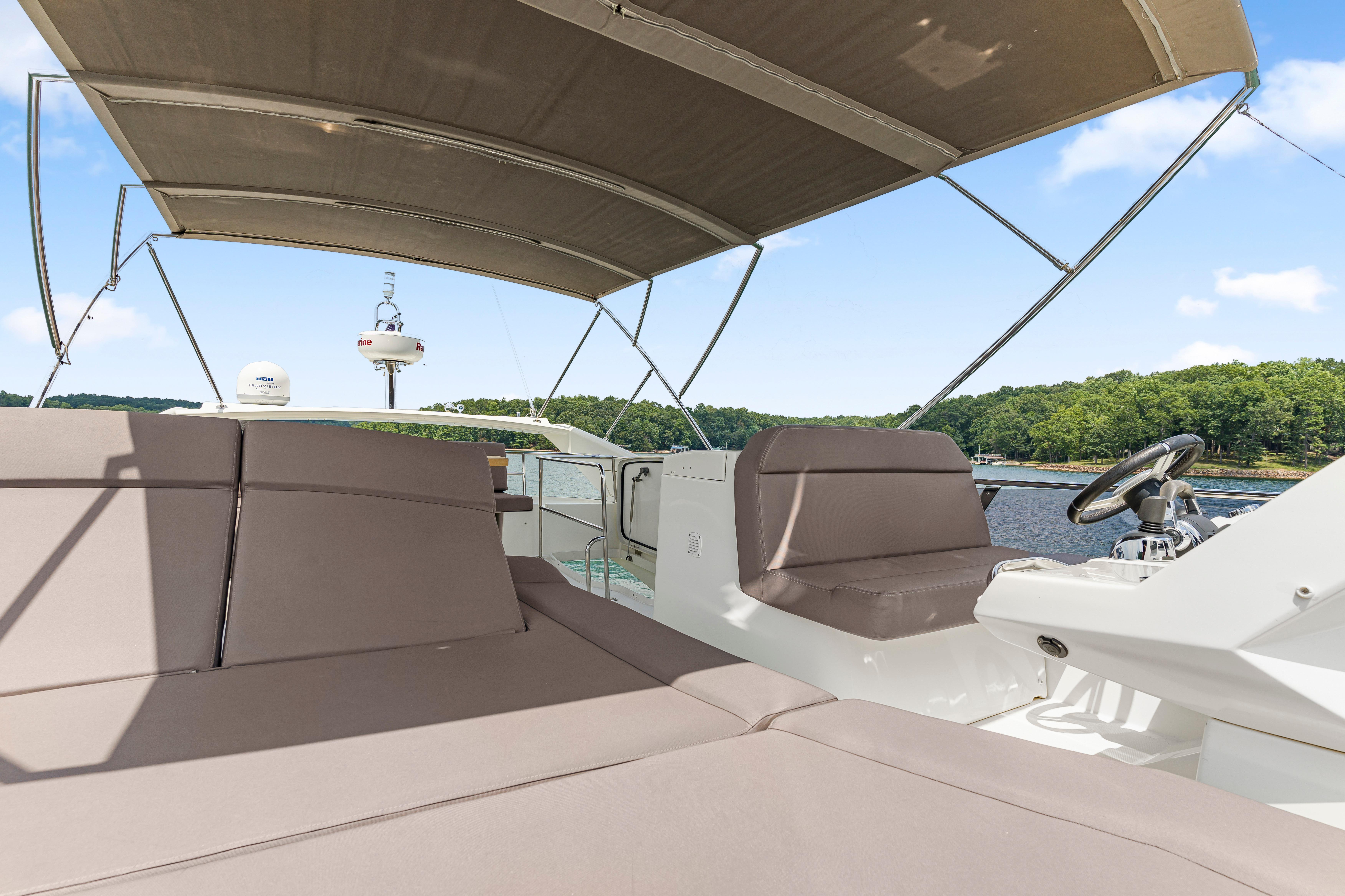 Luxurious 2017 Prestige 500 yacht with spacious deck and canopy, cruising on a serene lake.