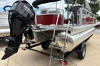 2026 Sun Tracker Bass Buggy 18 DLX pontoon boat with Mercury engine, docked on trailer.