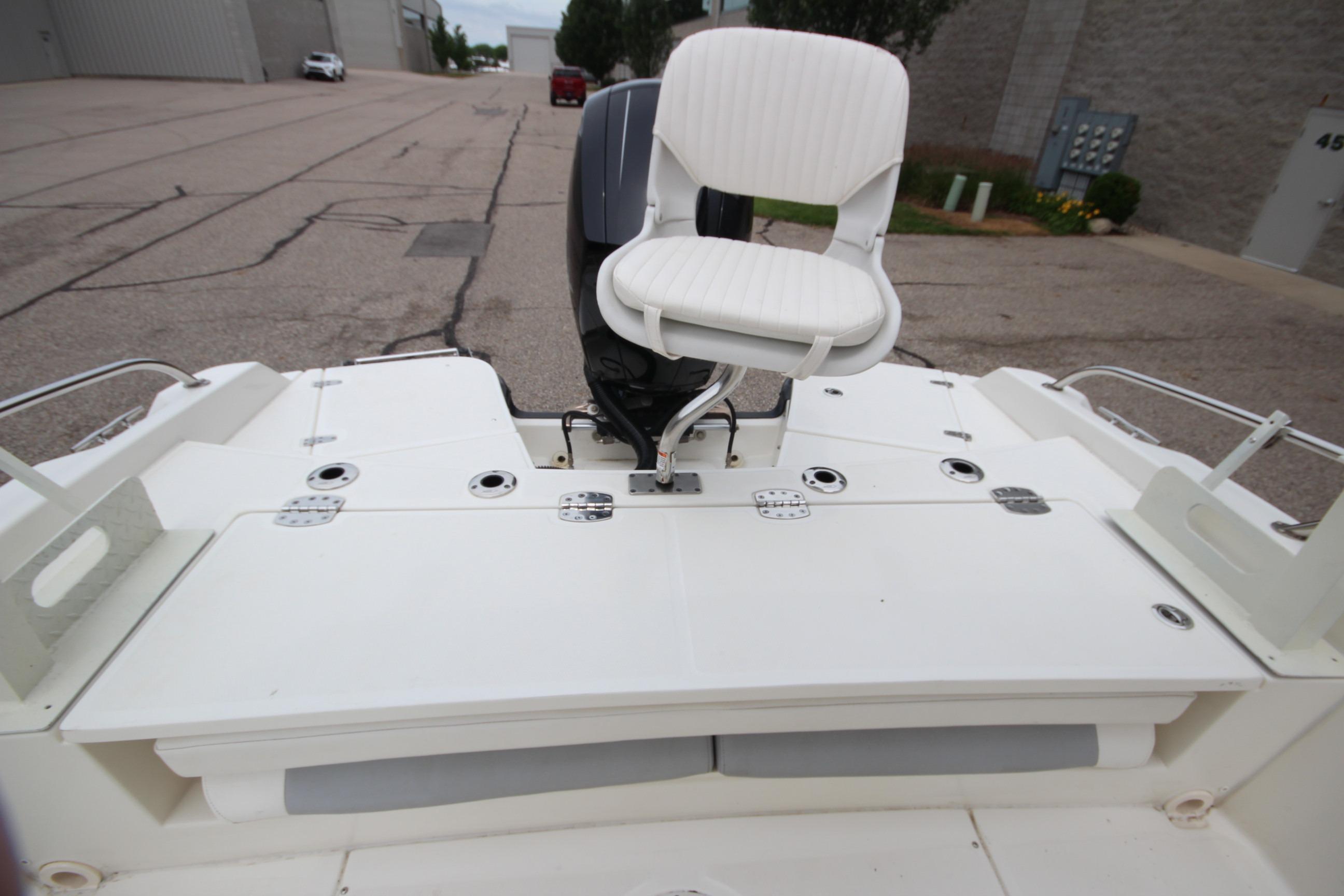 2014 Boston Whaler 210 Dauntless boat with white seating and motor, docked outdoors.