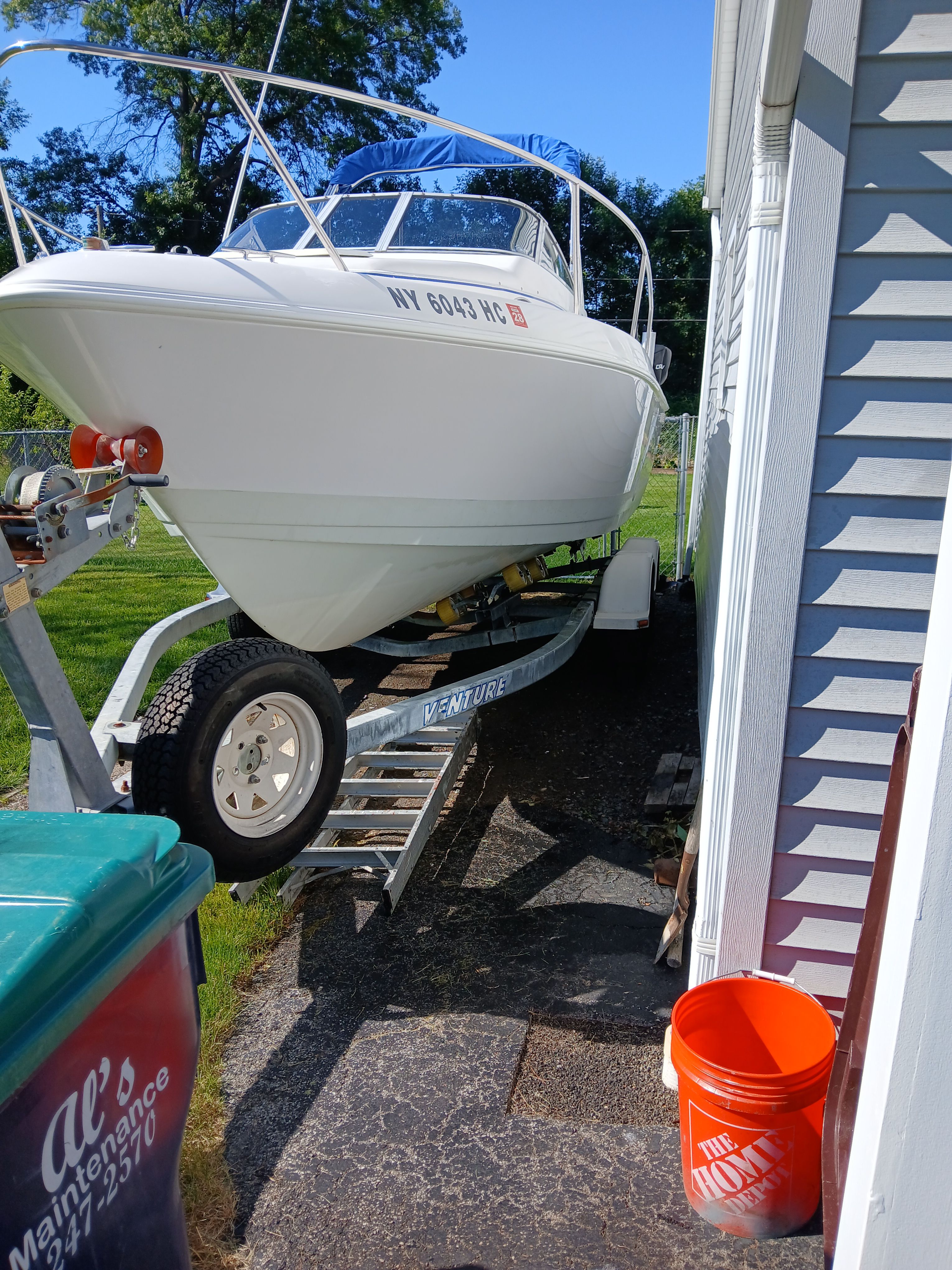 A 1999 Pro-Line 201 Walkaround boat on a trailer beside a house.