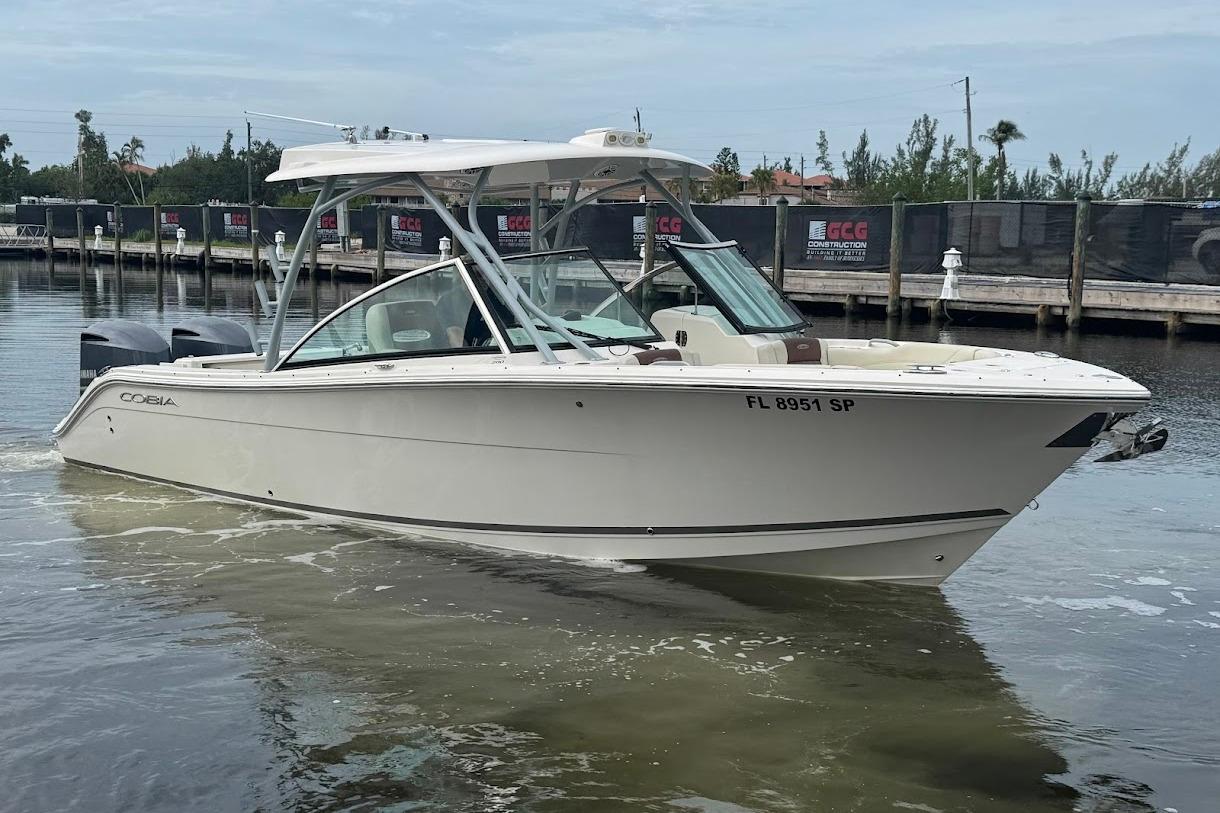2020 Cobia 280 Dual Console boat on water near a dock.
