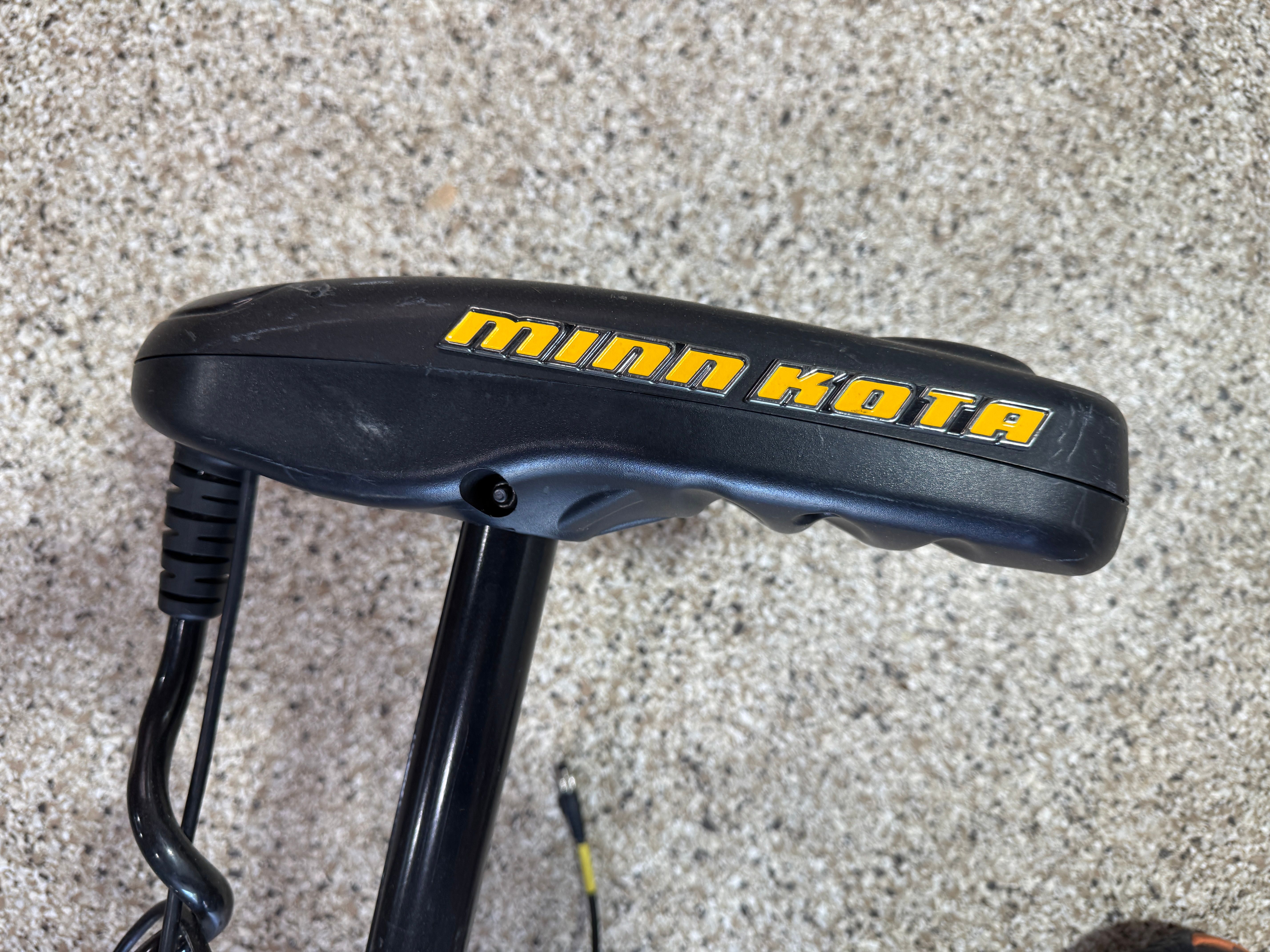 Close-up of a Minn Kota boat motor on a gravel surface.