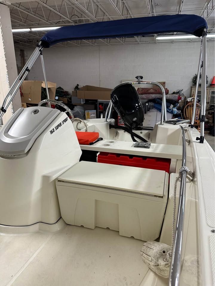 2020 Boston Whaler 160 with blue bimini top, helm console, and storage area.