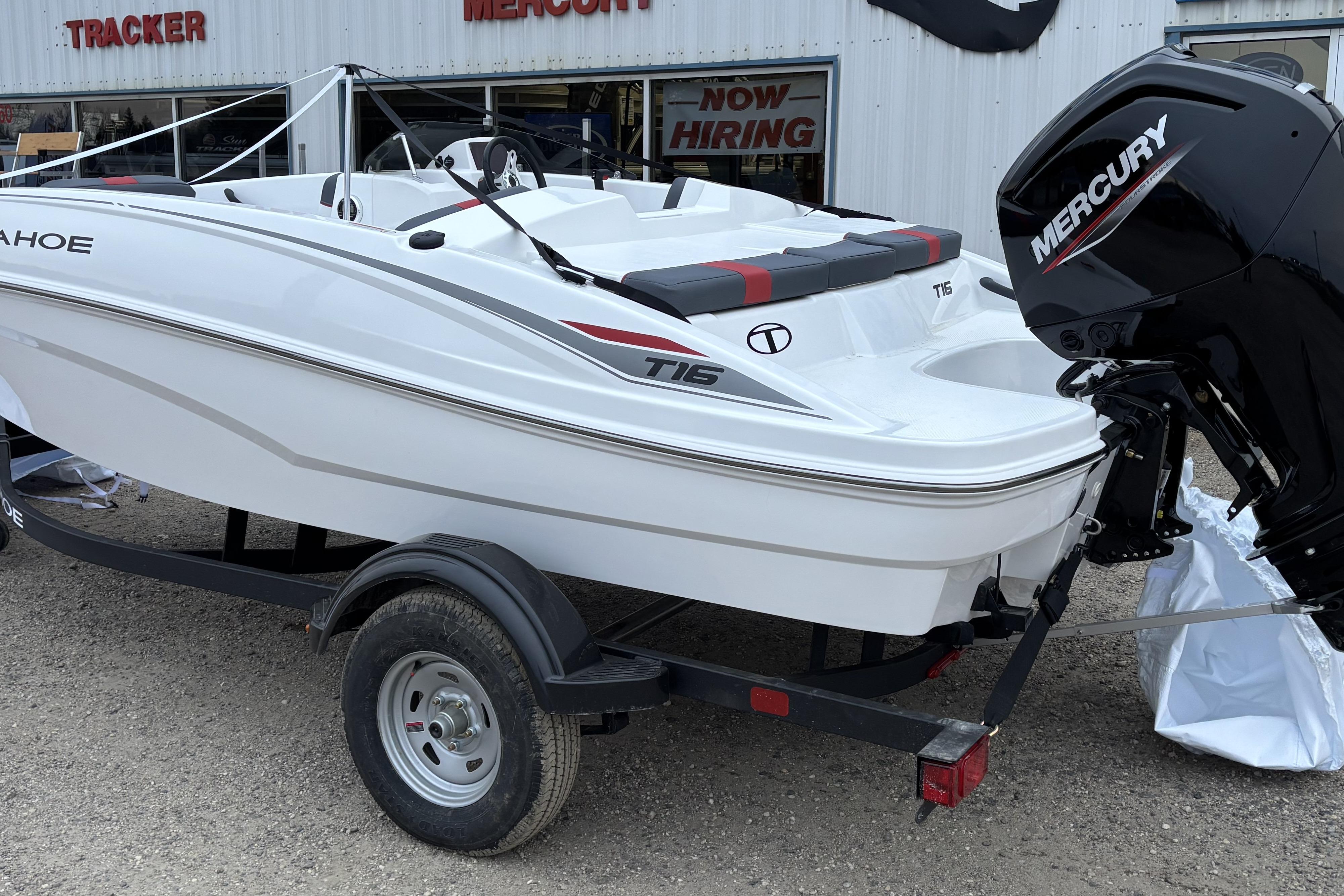 2026 Tahoe T16 boat with Mercury engine on a trailer, parked outside a dealership.