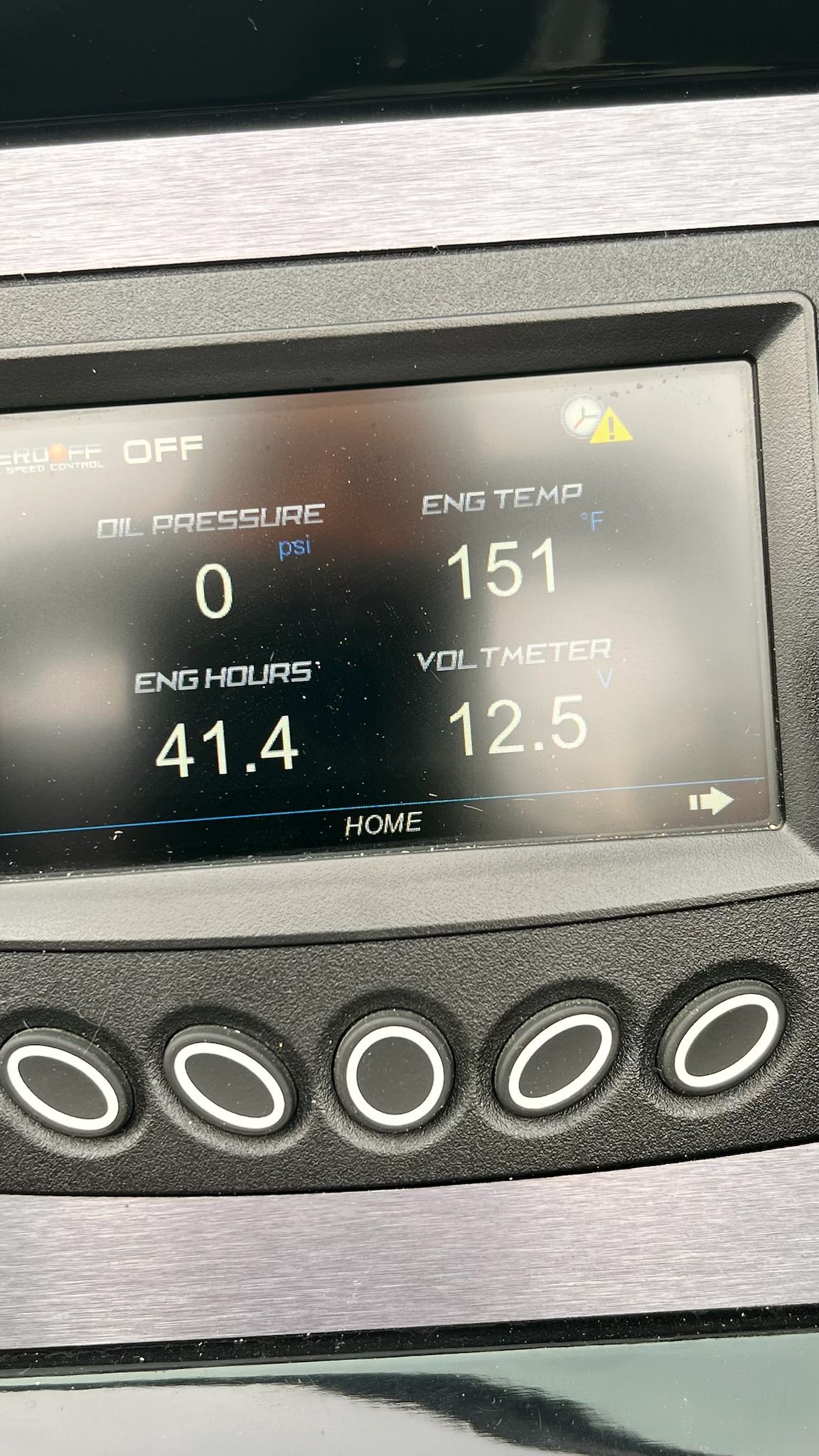 A digital dashboard displays oil pressure, engine temperature, engine hours, and voltmeter readings.