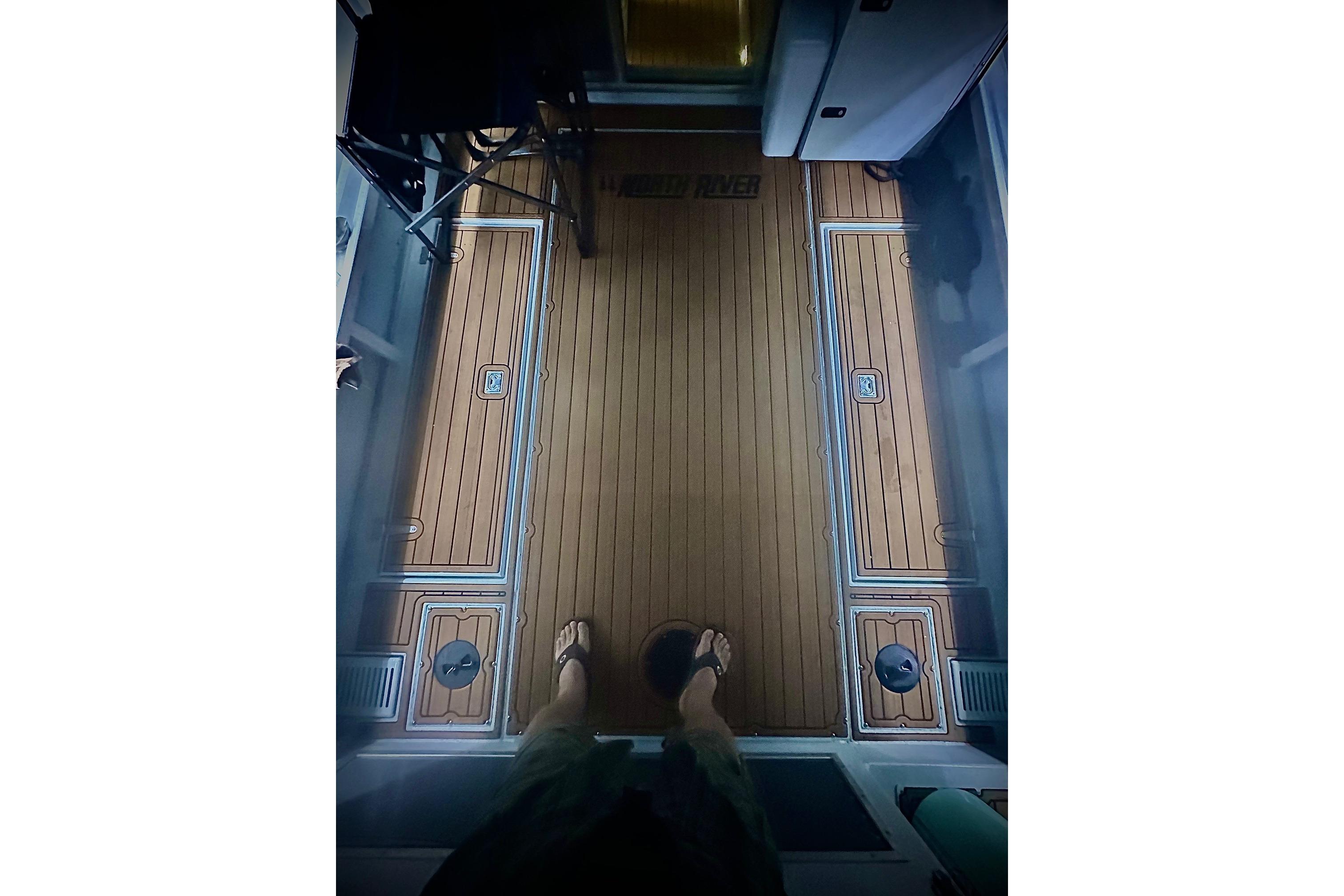 Interior view of 2023 North River 2500 boat with wooden flooring and storage compartments.