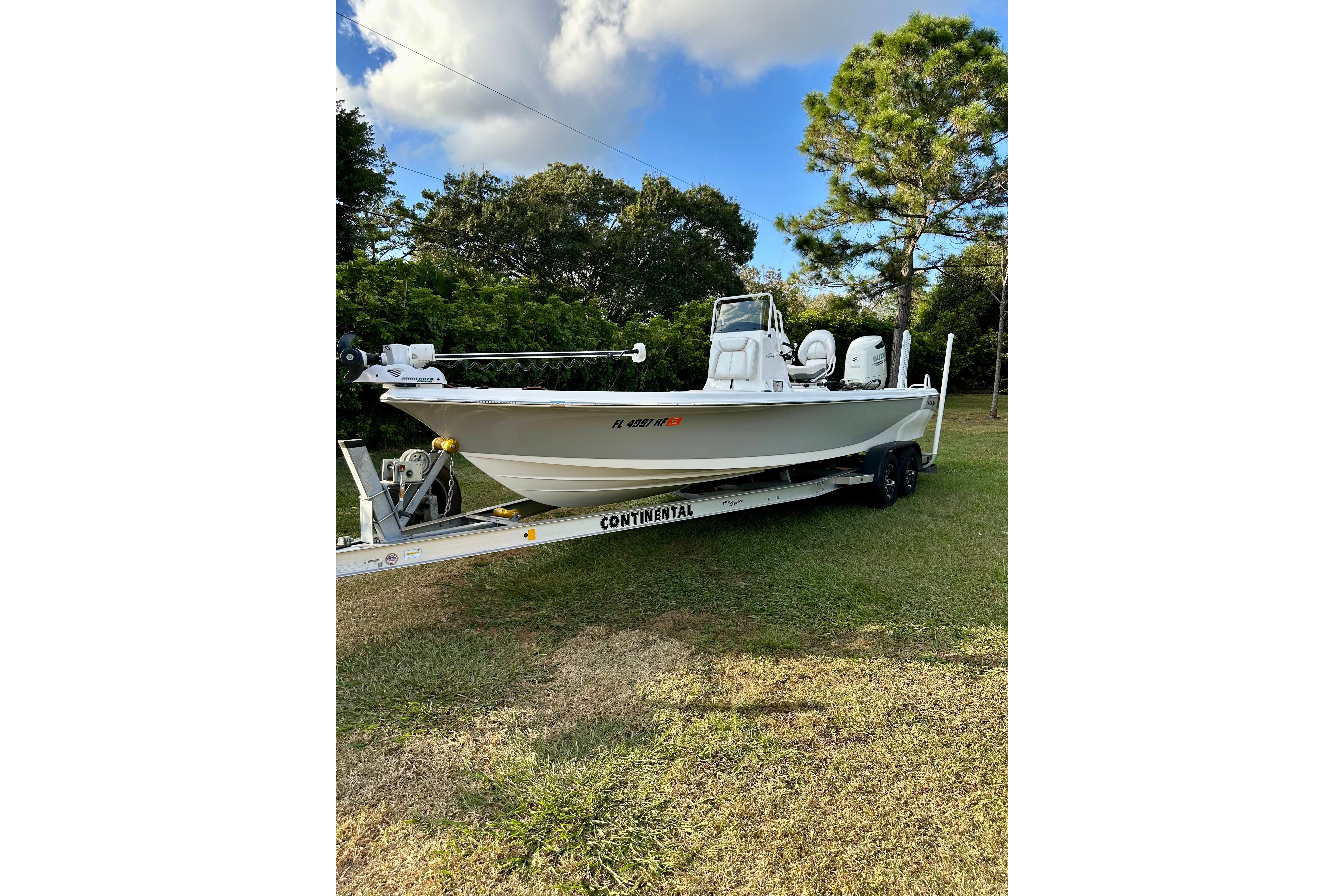 2017 Blue Wave 2400 PureBay boat on trailer, parked on grass under a blue sky.
