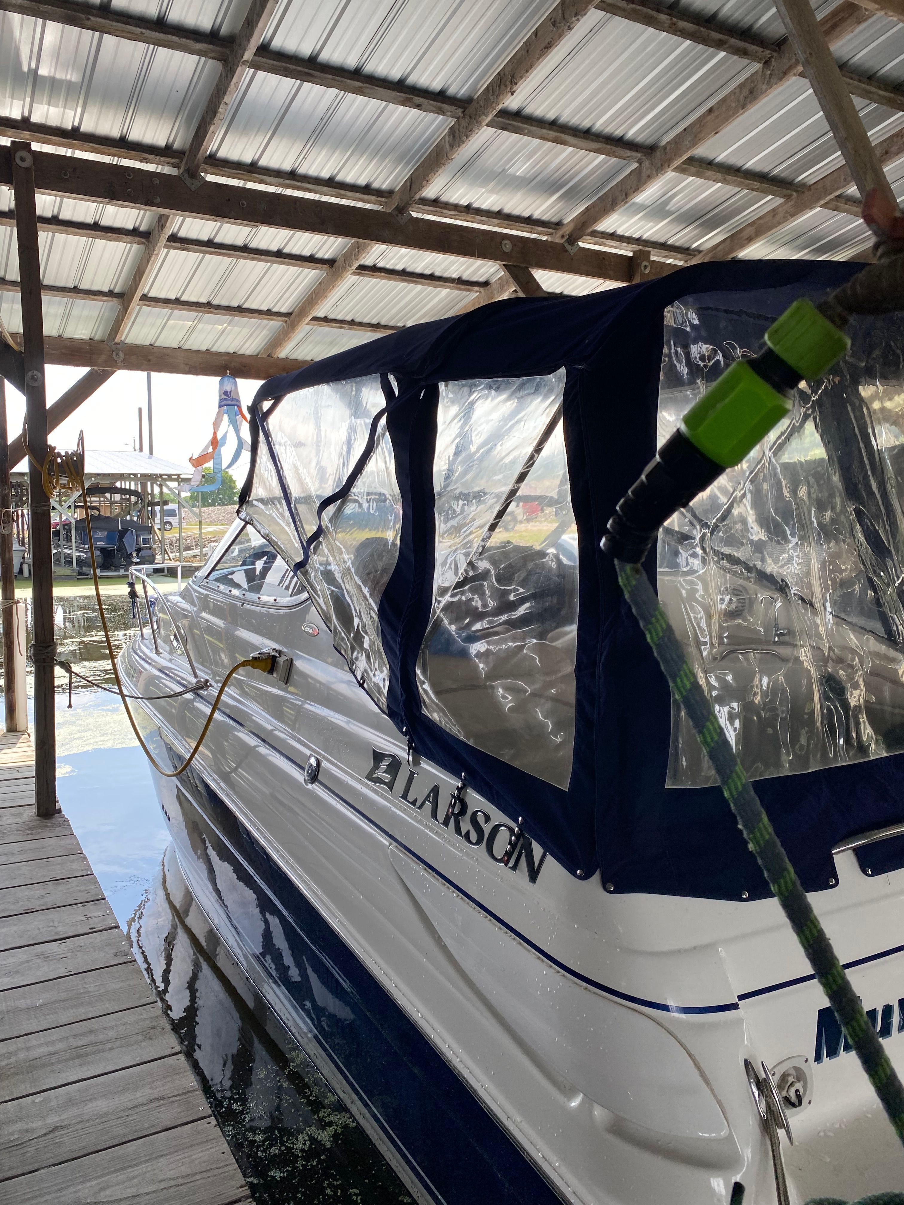 A 2005 Larson Cabrio 240 is docked in a covered boathouse.